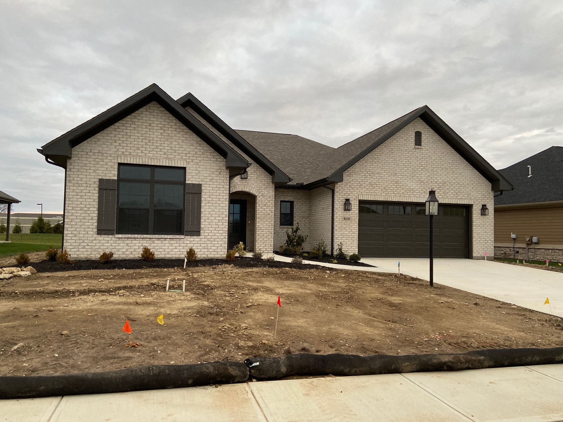 A large brick house with a garage and a lot of dirt in front of it.