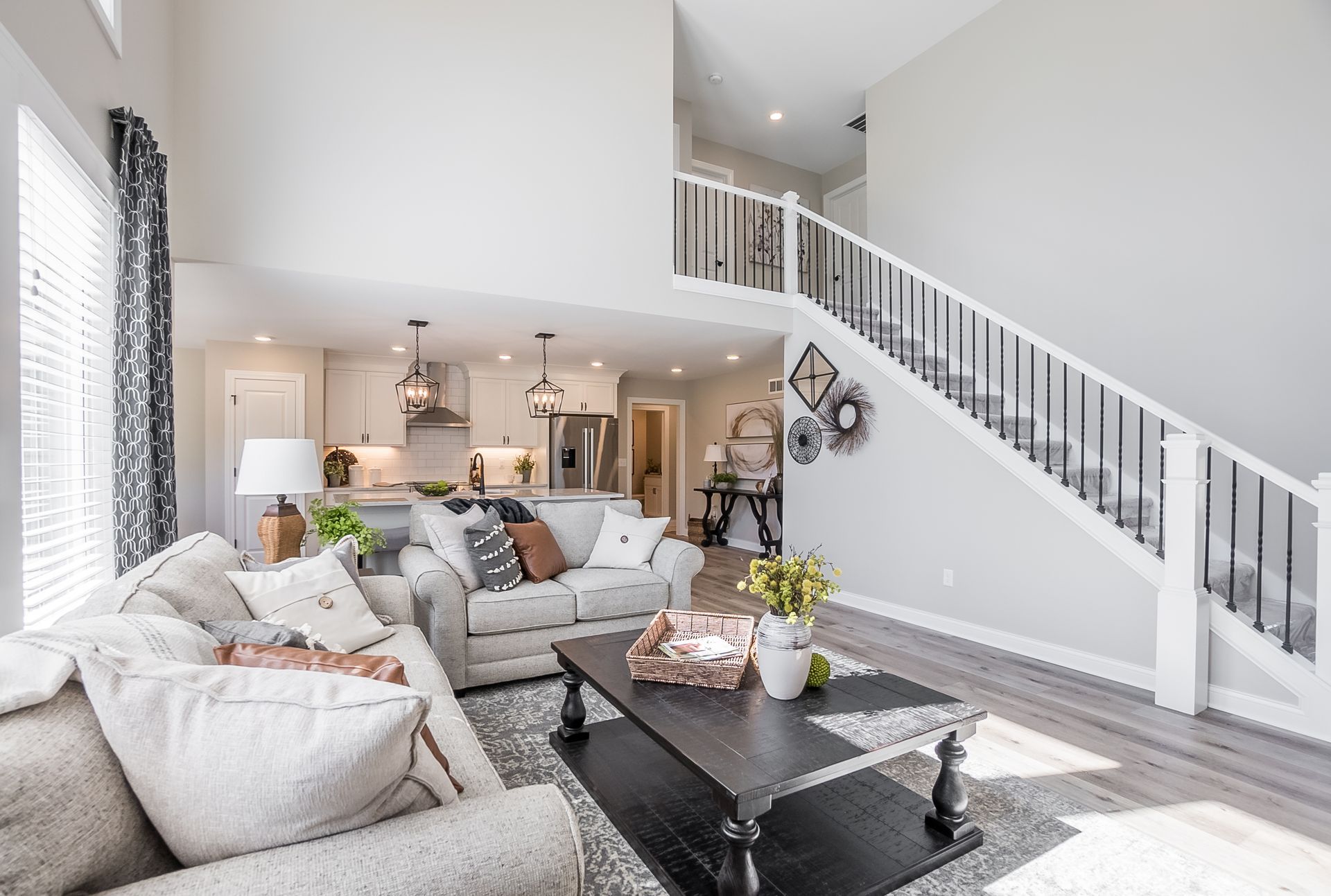 A living room with a couch , chair , coffee table and stairs leading up to the second floor.