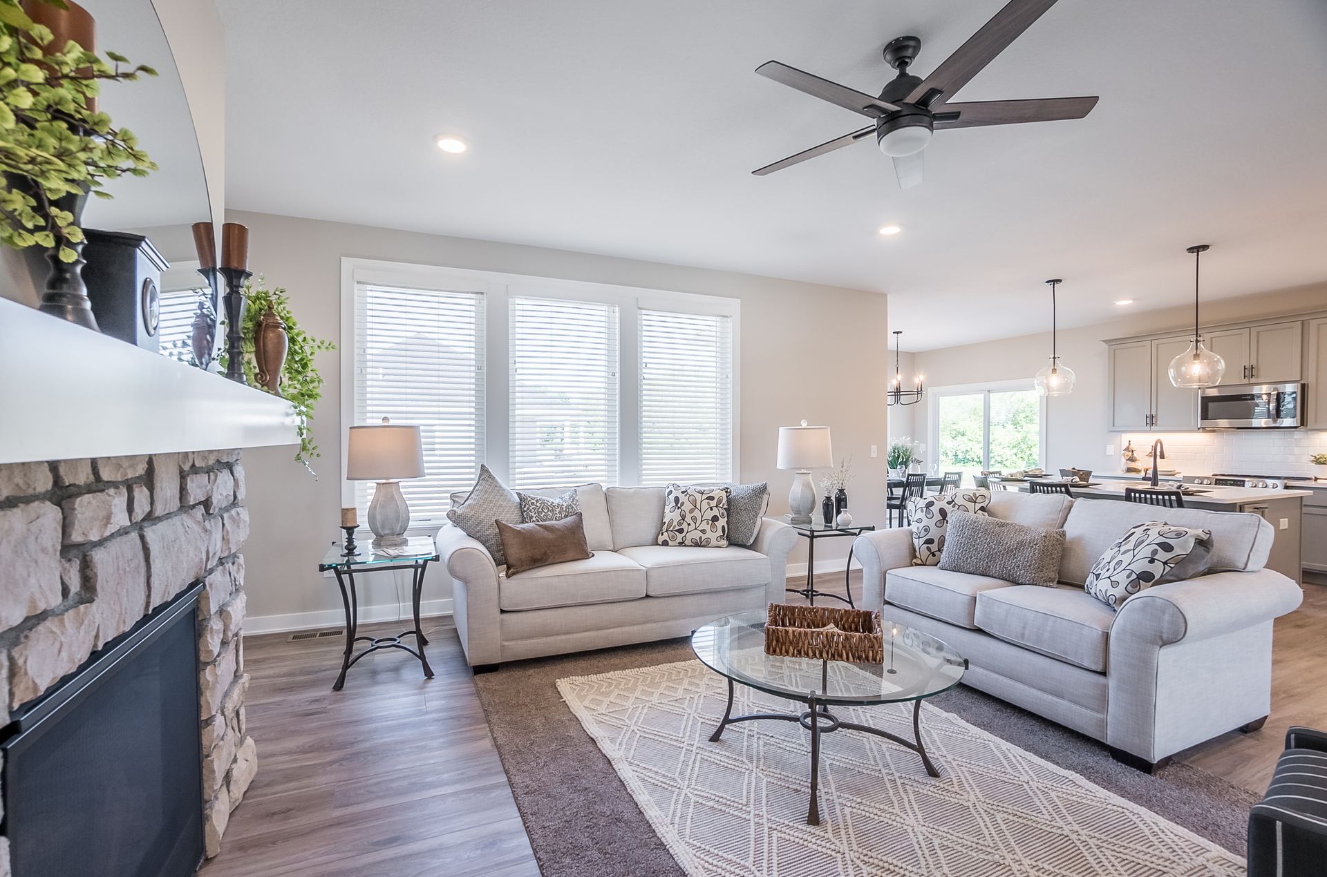 A living room with two couches , a fireplace , and a ceiling fan.