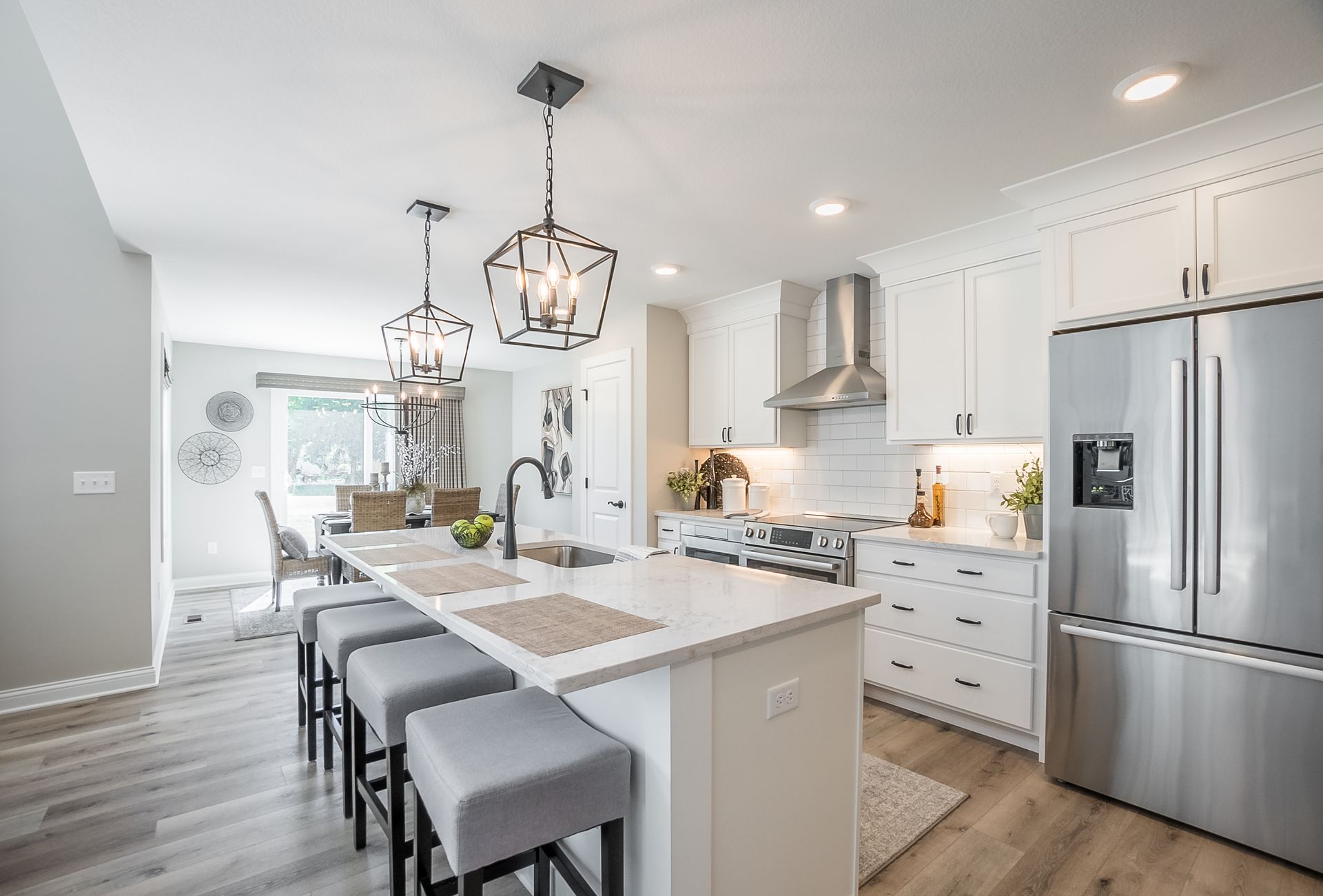 A kitchen with white cabinets , stainless steel appliances , and a large island.