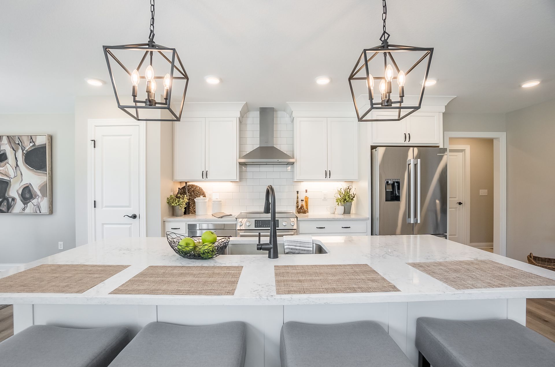A kitchen with white cabinets , stainless steel appliances , a sink , and a refrigerator.