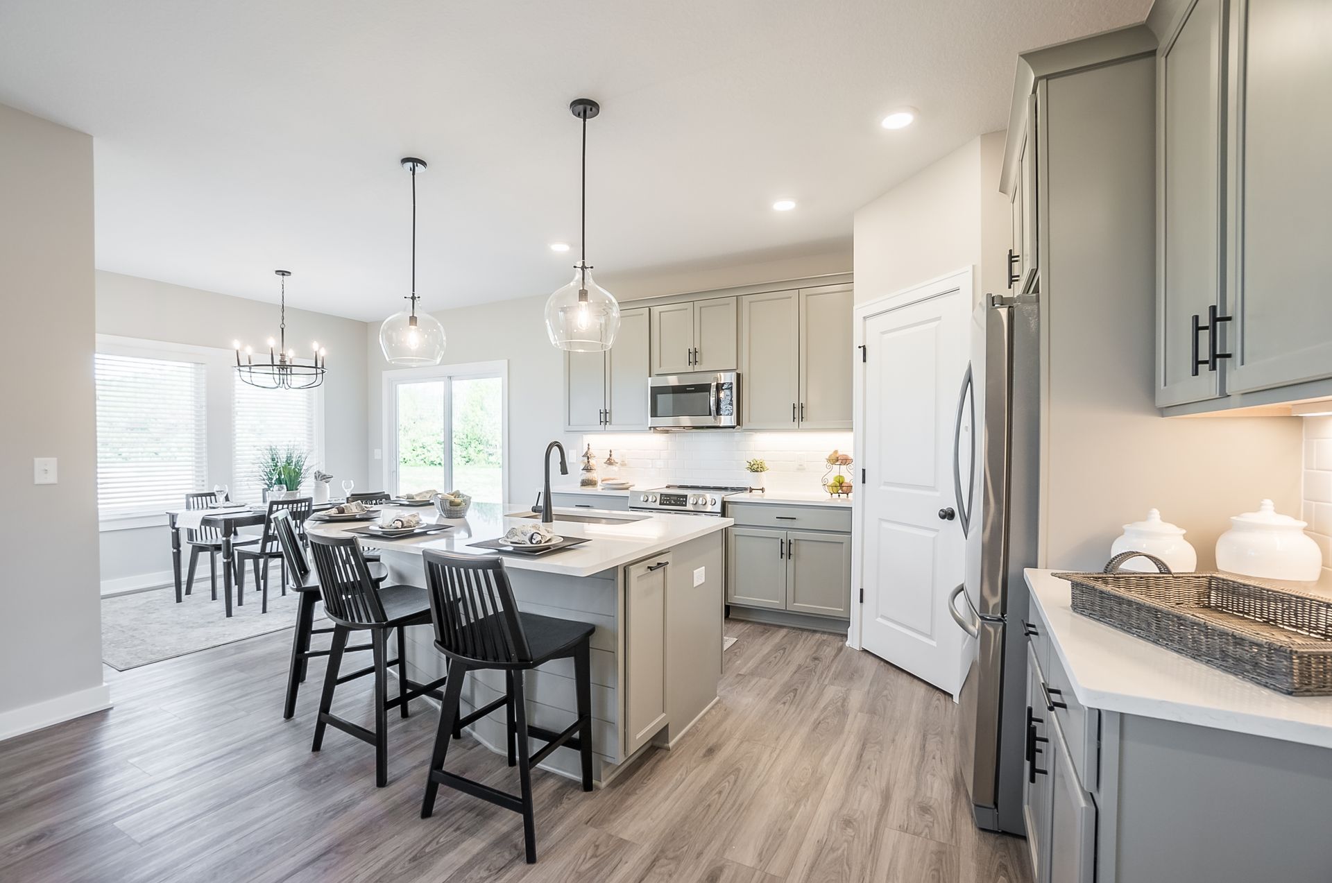 A kitchen with a large island and stools and a dining room in the background.