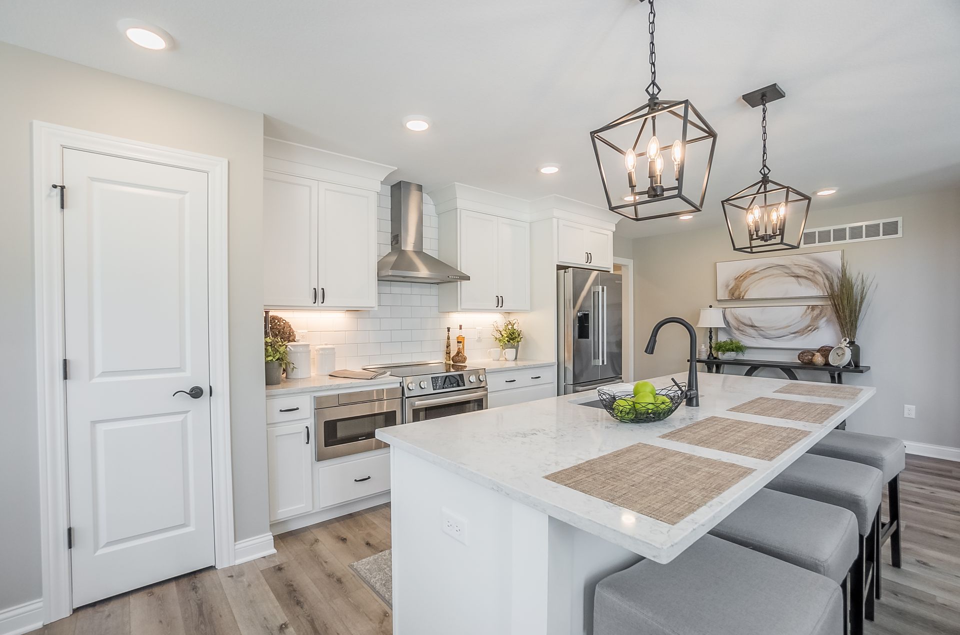 A kitchen with white cabinets , stainless steel appliances , and a large island.