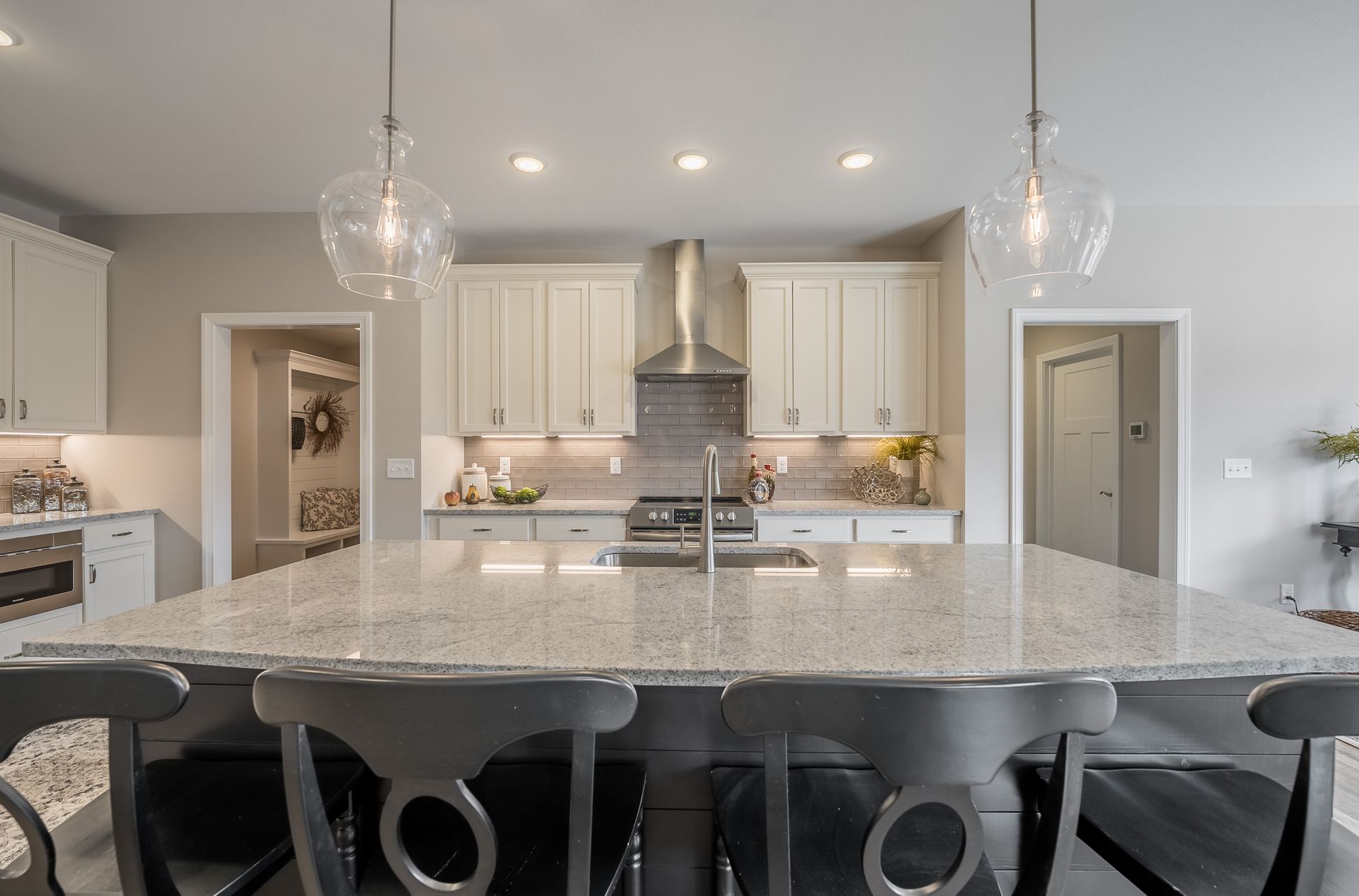 A kitchen with white cabinets , granite counter tops , stainless steel appliances and a large island.