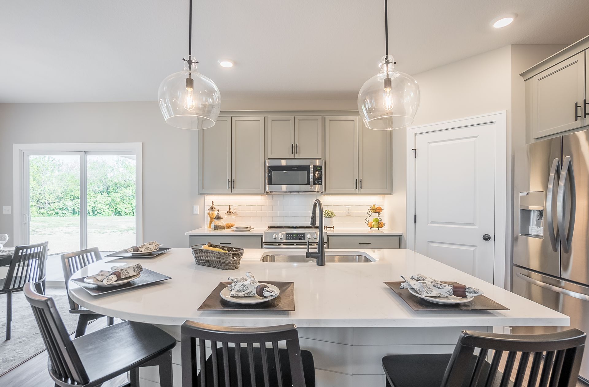 A kitchen with a large island in the middle and a dining table and chairs.