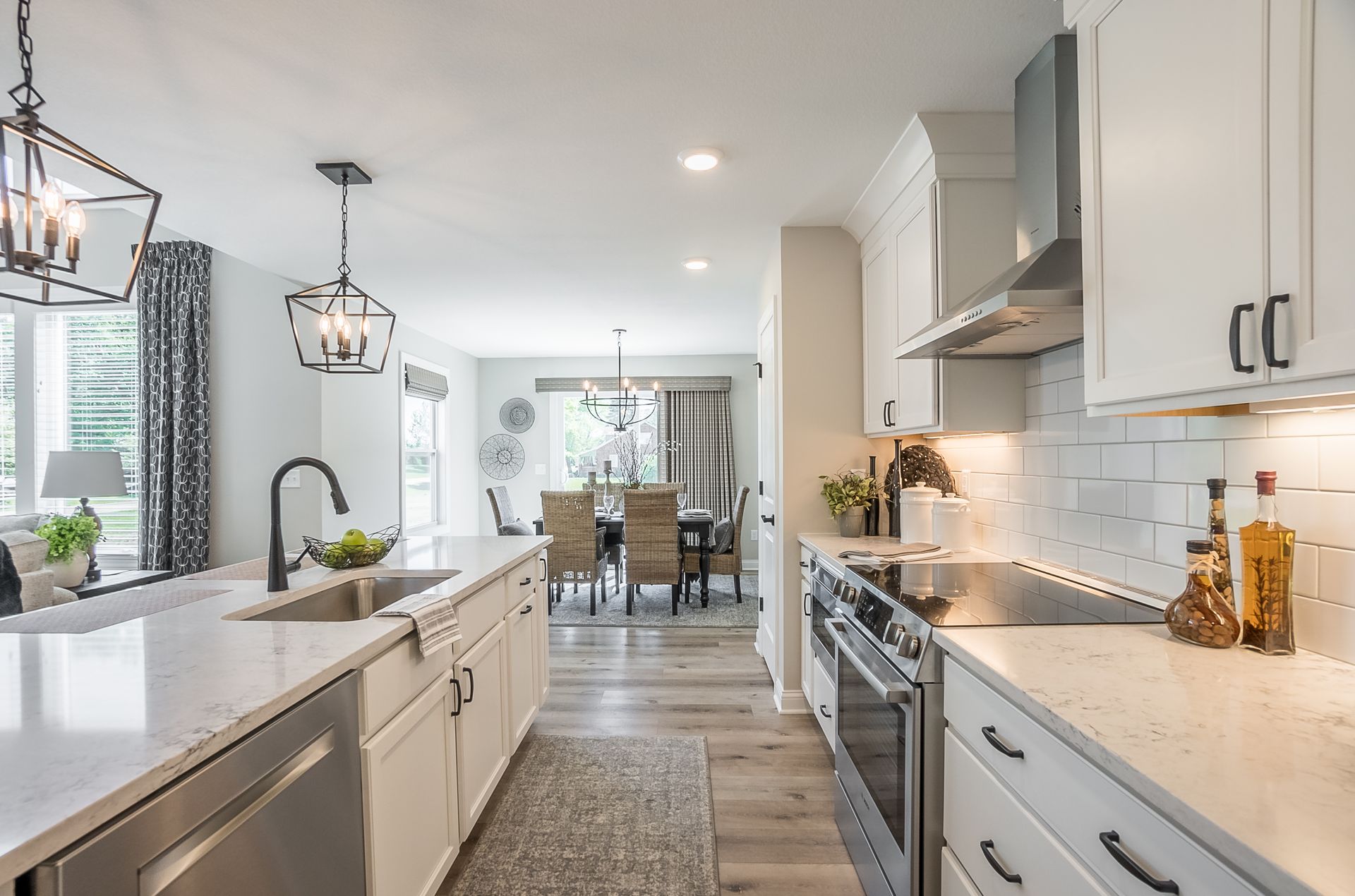 A kitchen with white cabinets and stainless steel appliances and a dining room in the background.