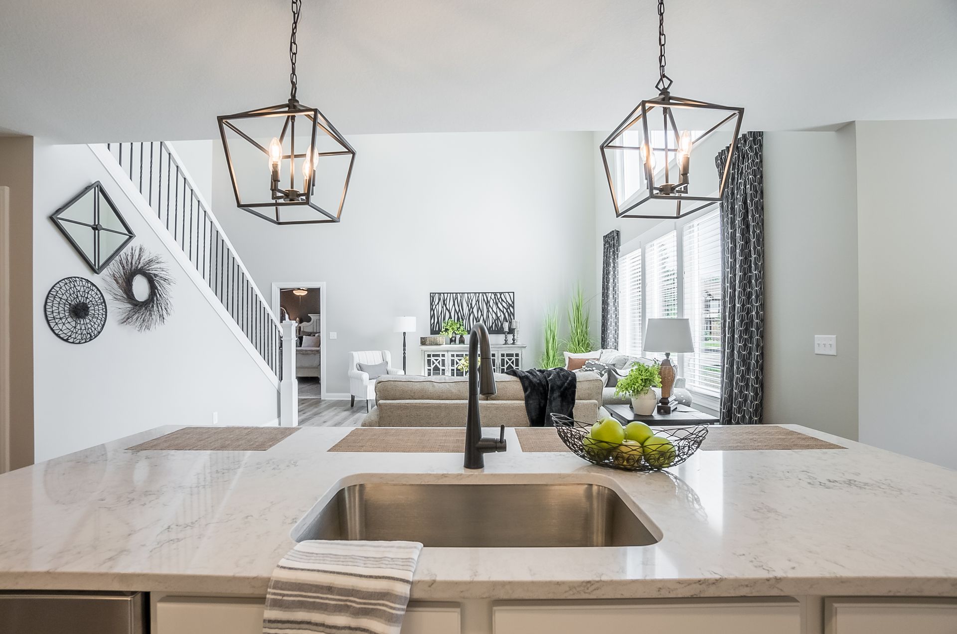 A kitchen with a sink and a living room in the background.