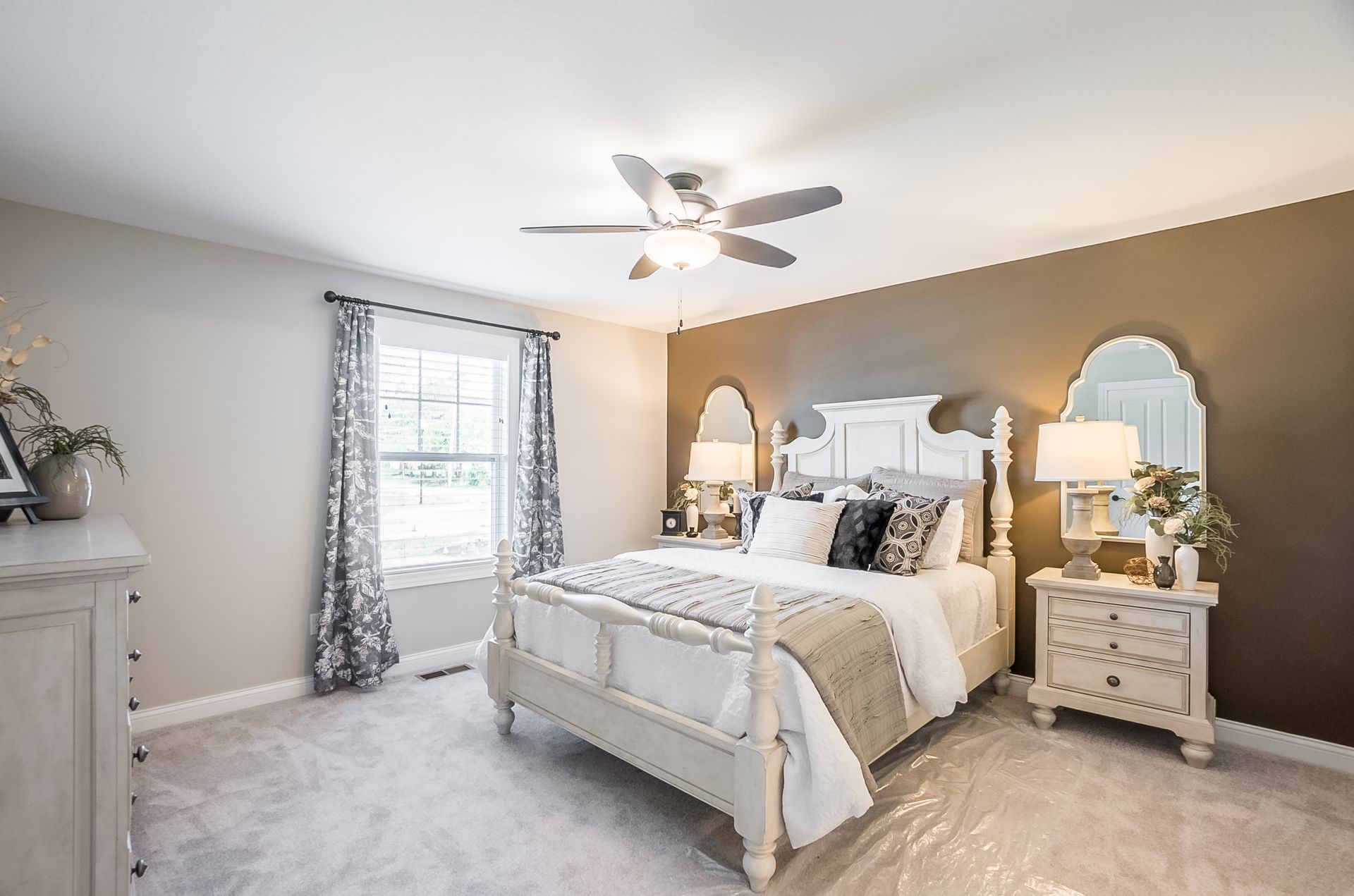A bedroom with a bed , nightstand , dresser and ceiling fan.