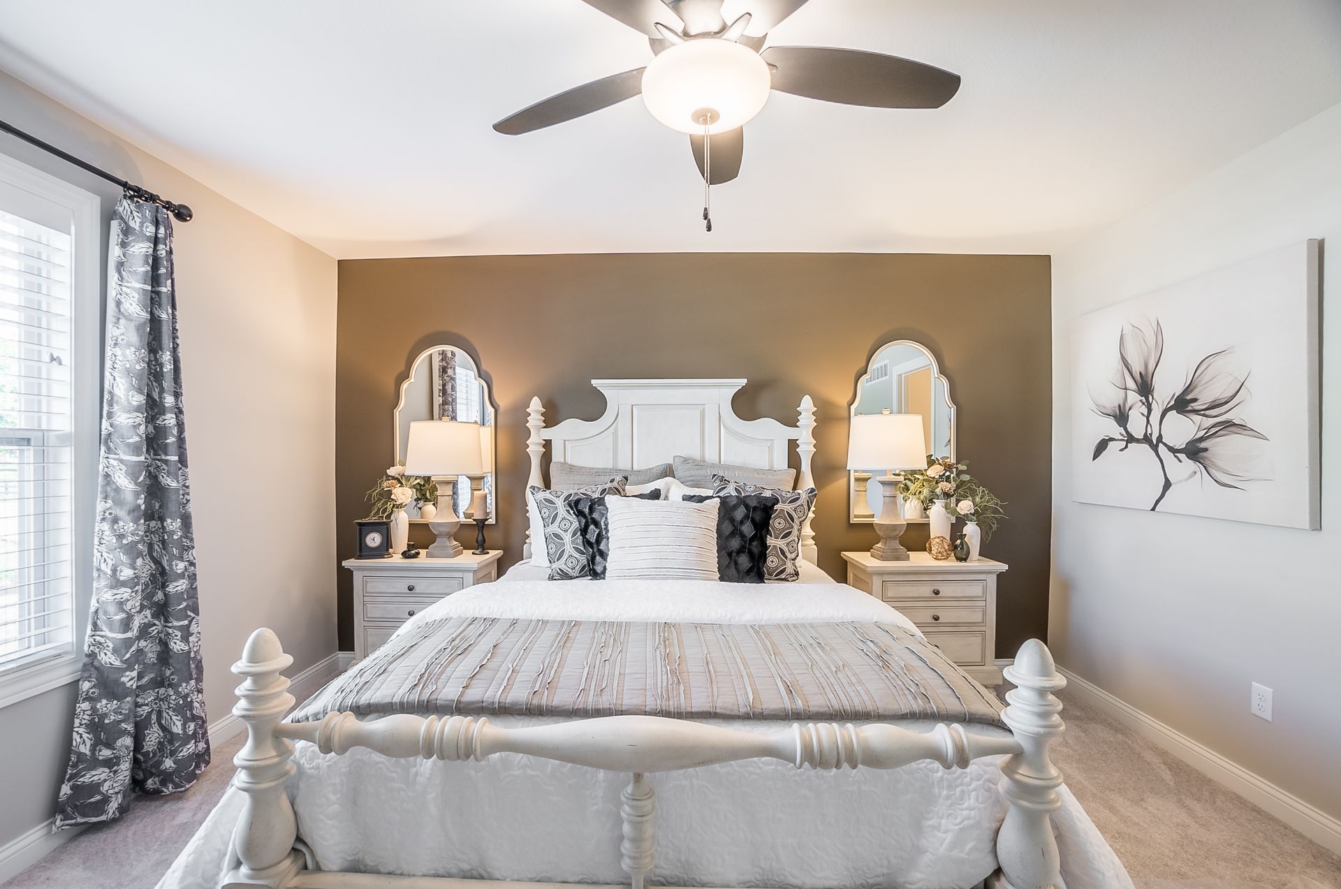 A bedroom with a bed , nightstands , mirrors and a ceiling fan.