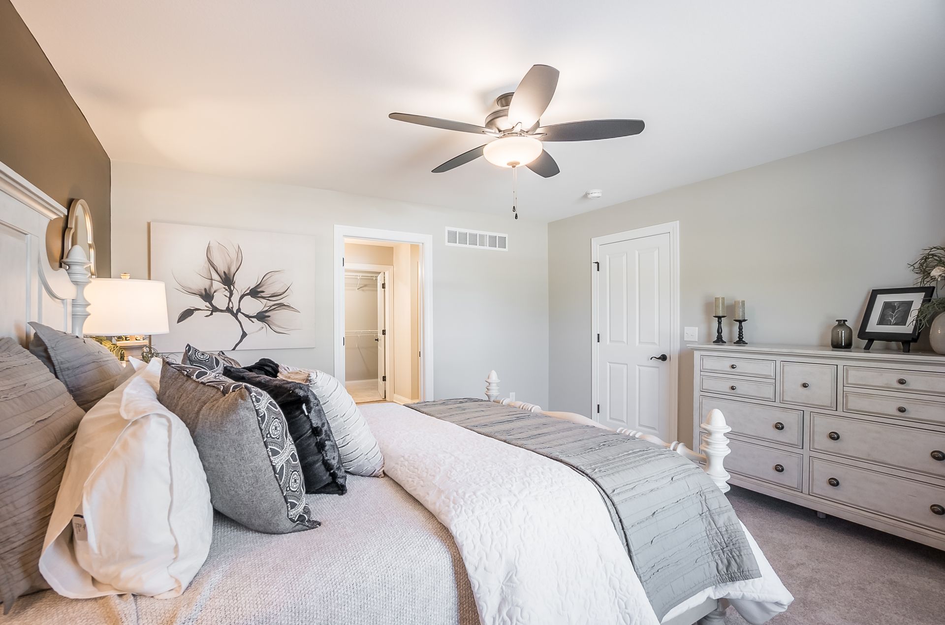 A bedroom with a bed , dresser , and ceiling fan.