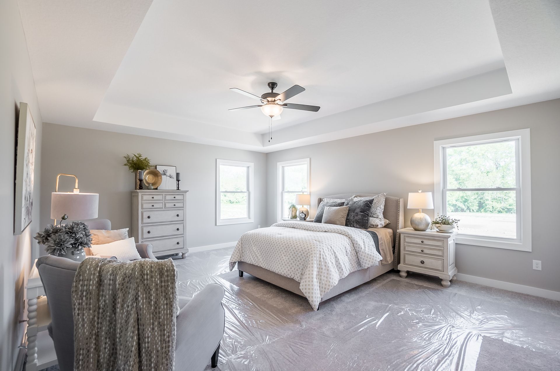 A bedroom with a bed , dresser , nightstand , chair and ceiling fan.