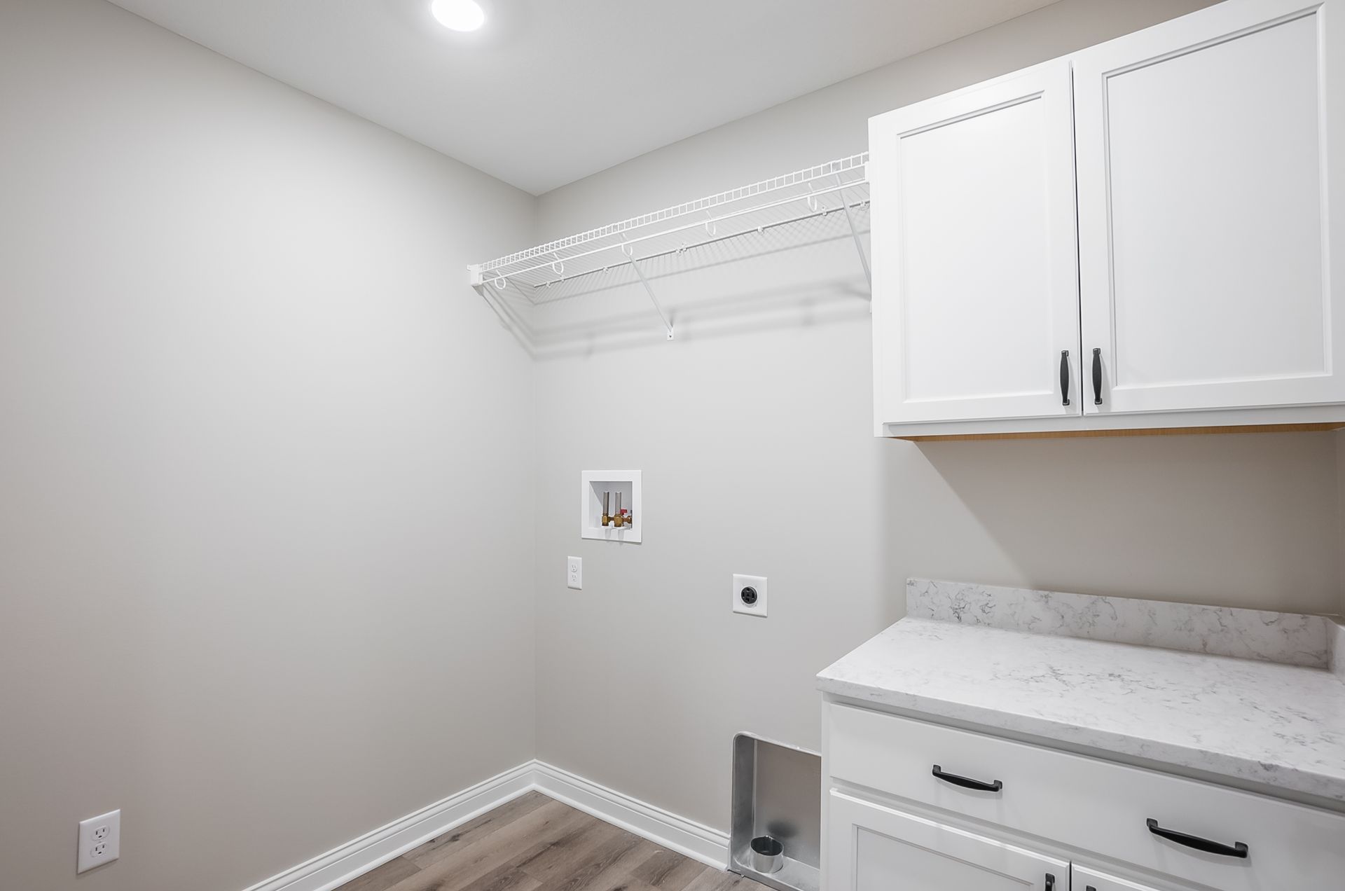 A laundry room with white cabinets and a sink.