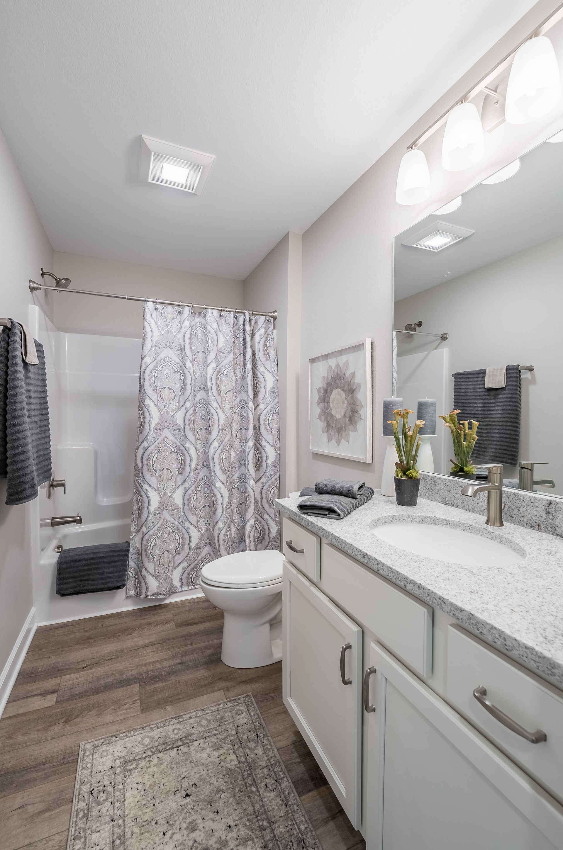 A bathroom with a toilet , sink , shower and mirror.