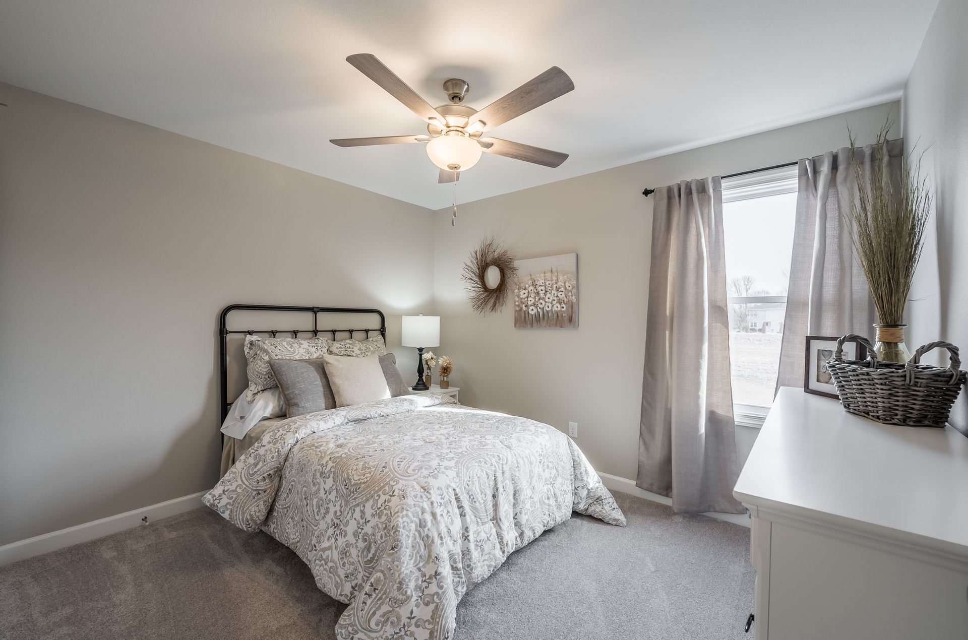 A bedroom with a bed , dresser , and ceiling fan.