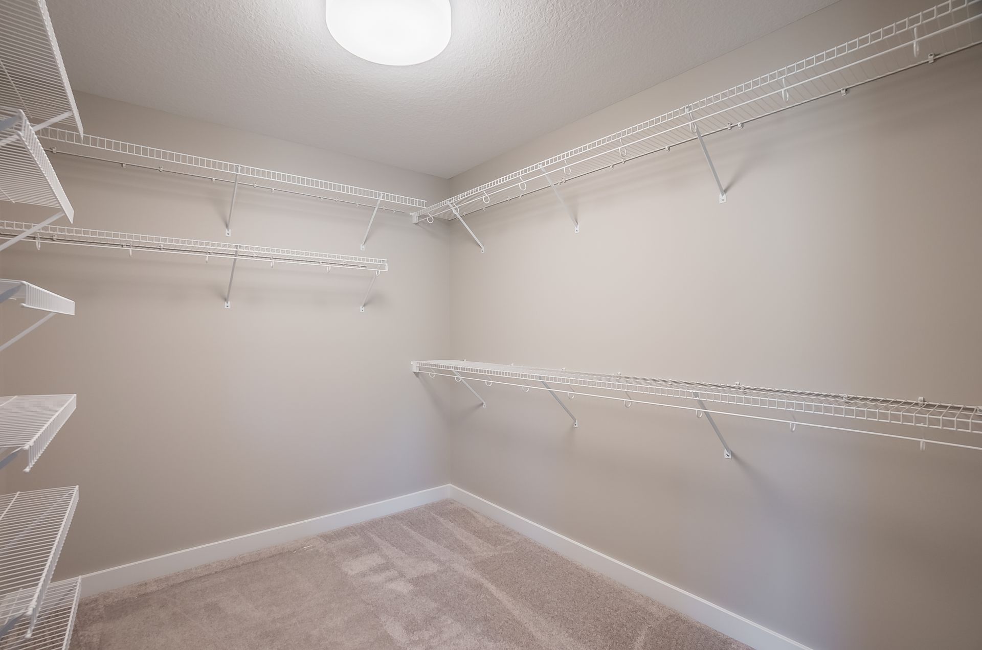 An empty walk in closet with shelves and a light.