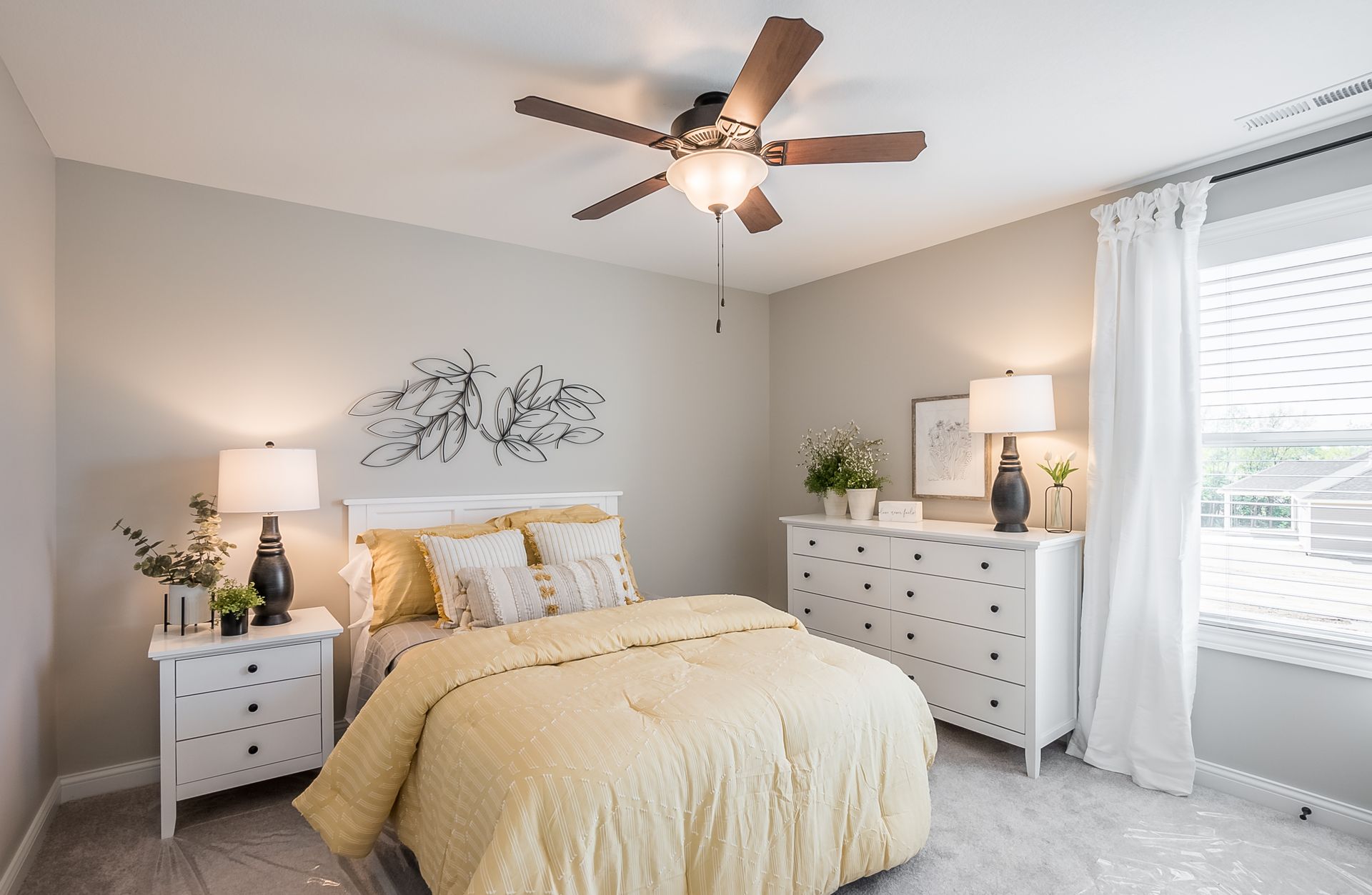 A bedroom with a bed , dresser , nightstand and ceiling fan.