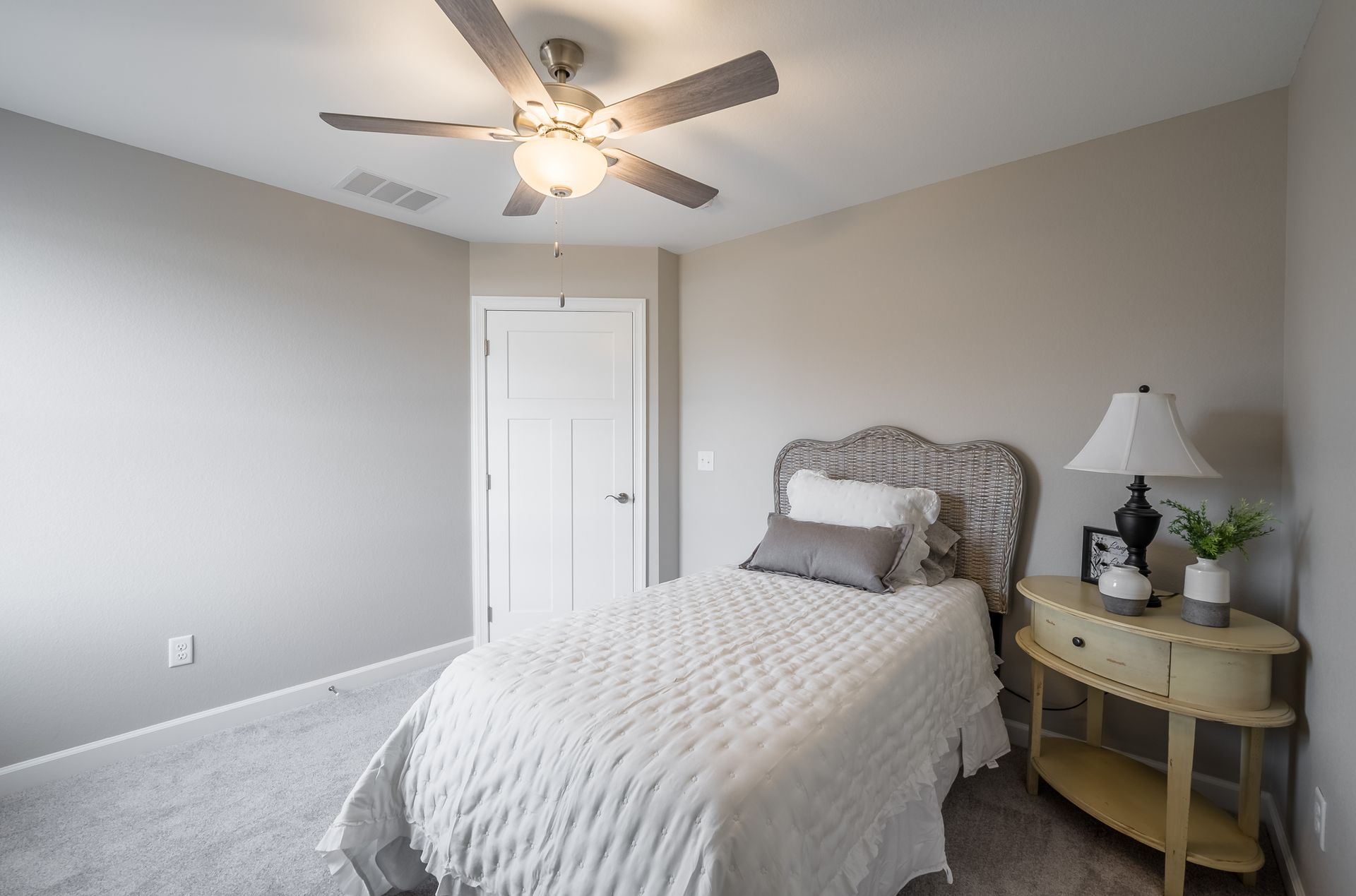 A bedroom with a single bed and a ceiling fan