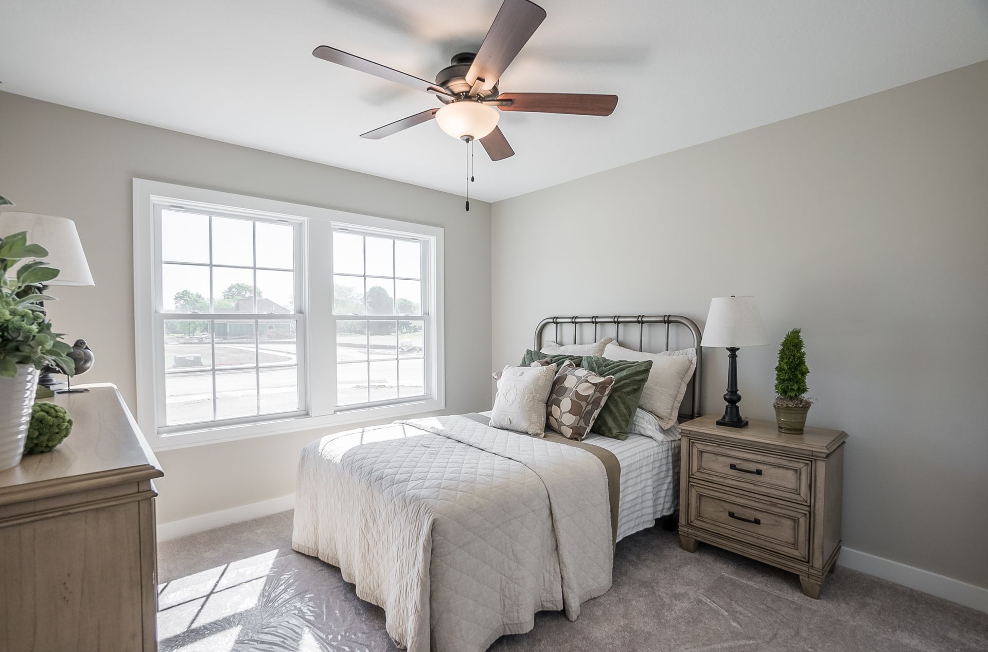 A bedroom with a bed , nightstand , dresser and ceiling fan.
