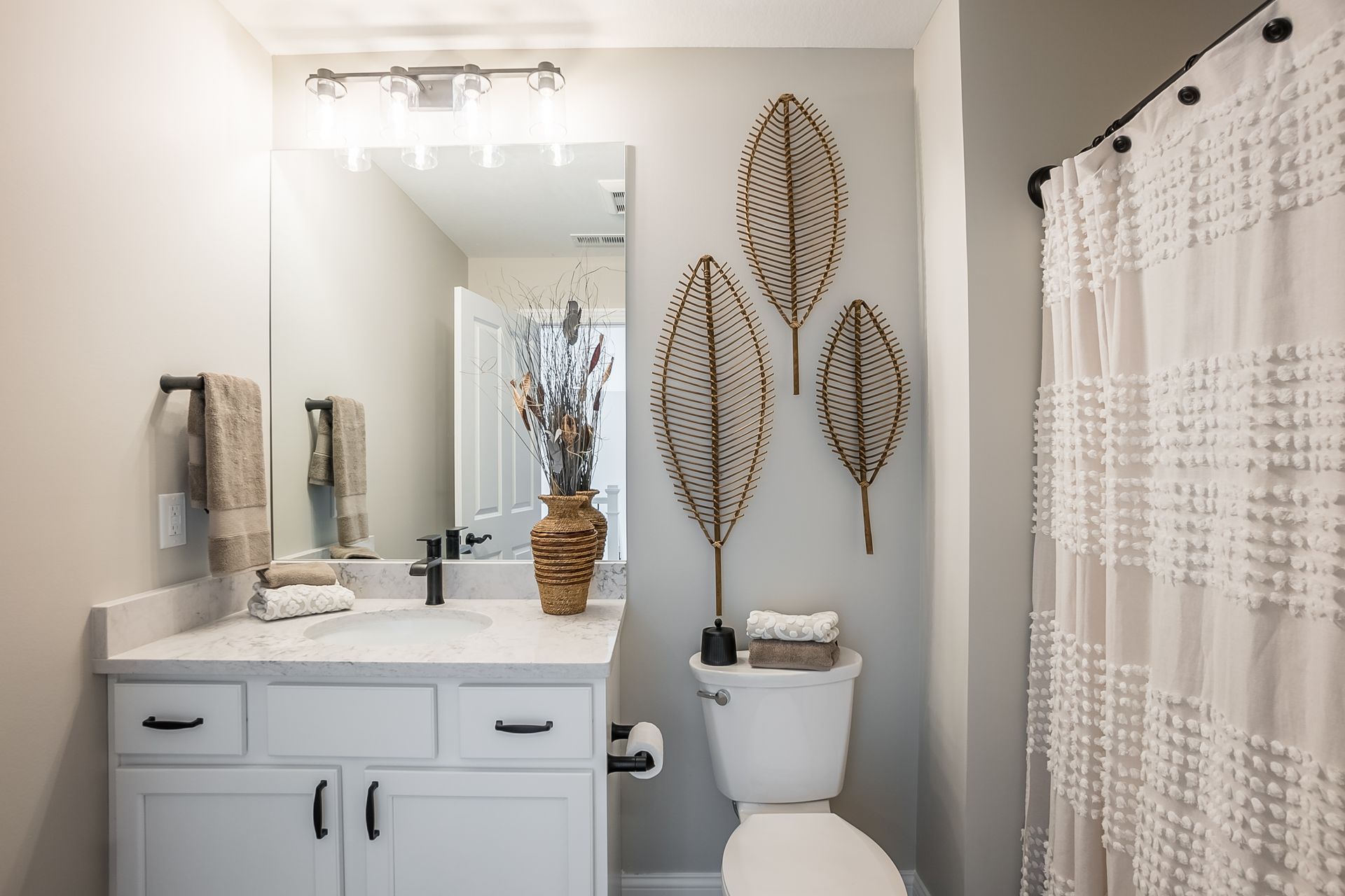 A bathroom with a toilet , sink , mirror and shower curtain.