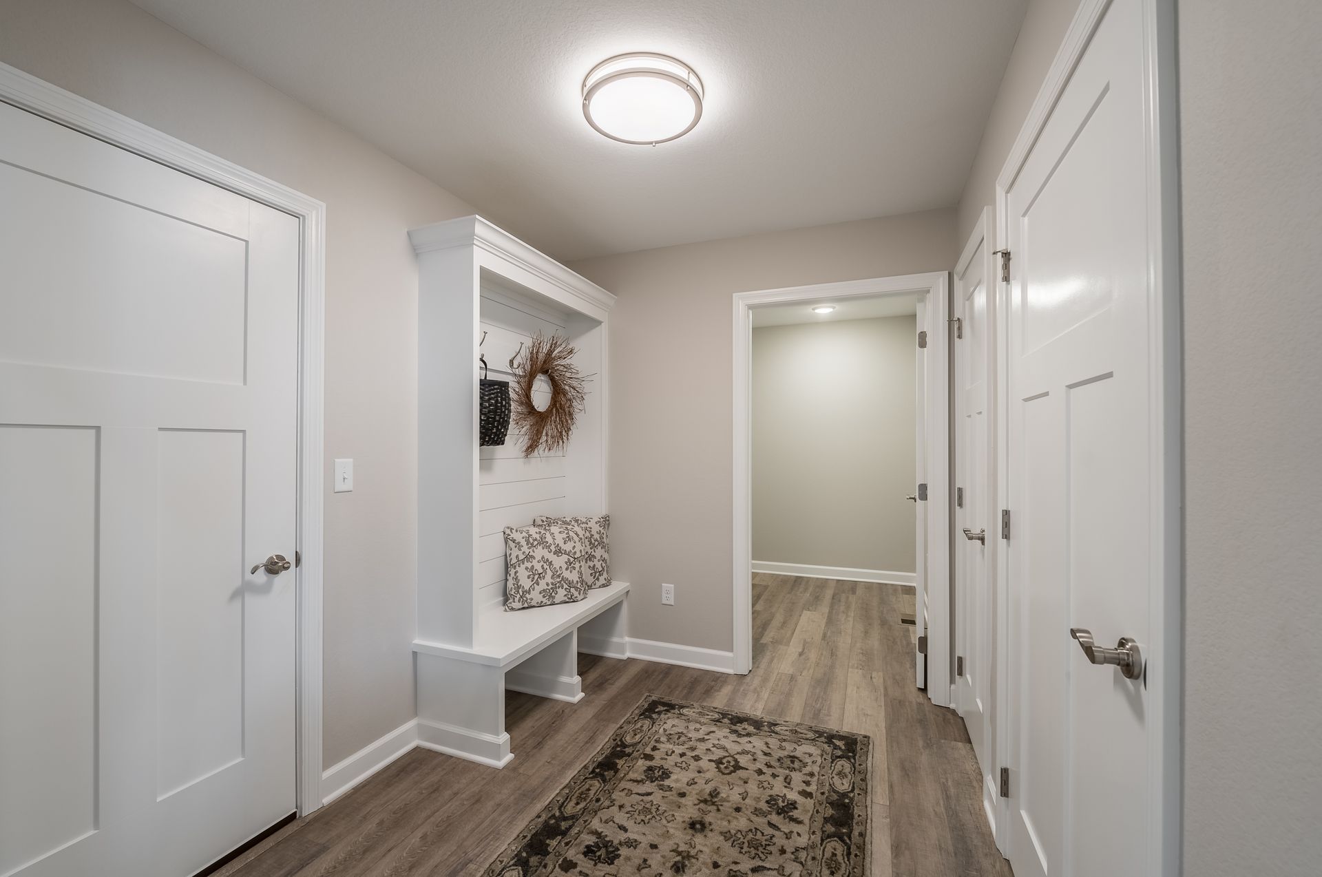 A hallway with a bench and a rug in a house.