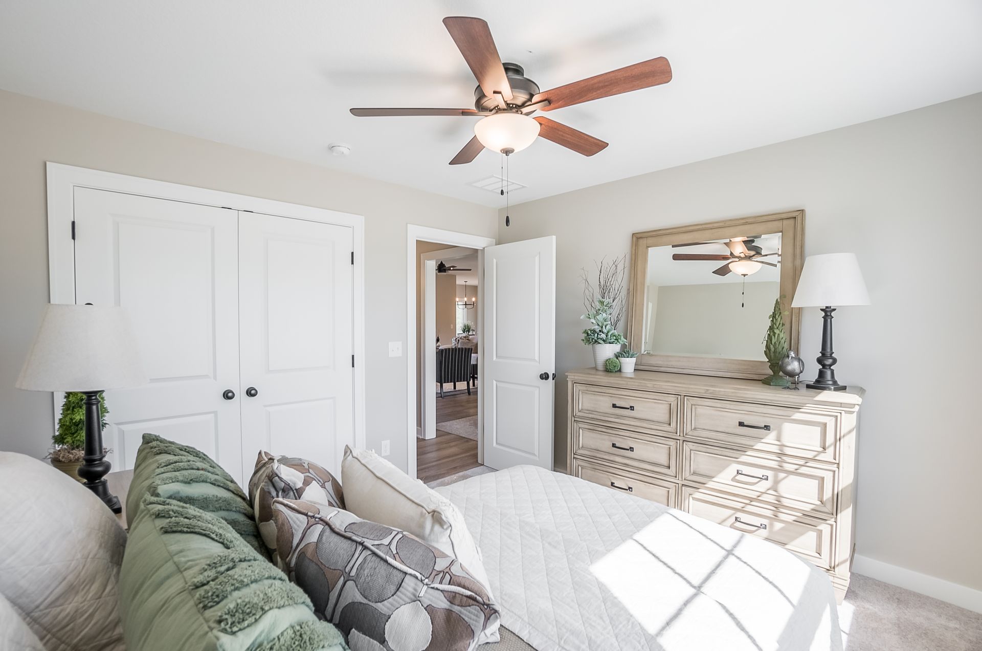A bedroom with a bed , dresser , mirror and ceiling fan.