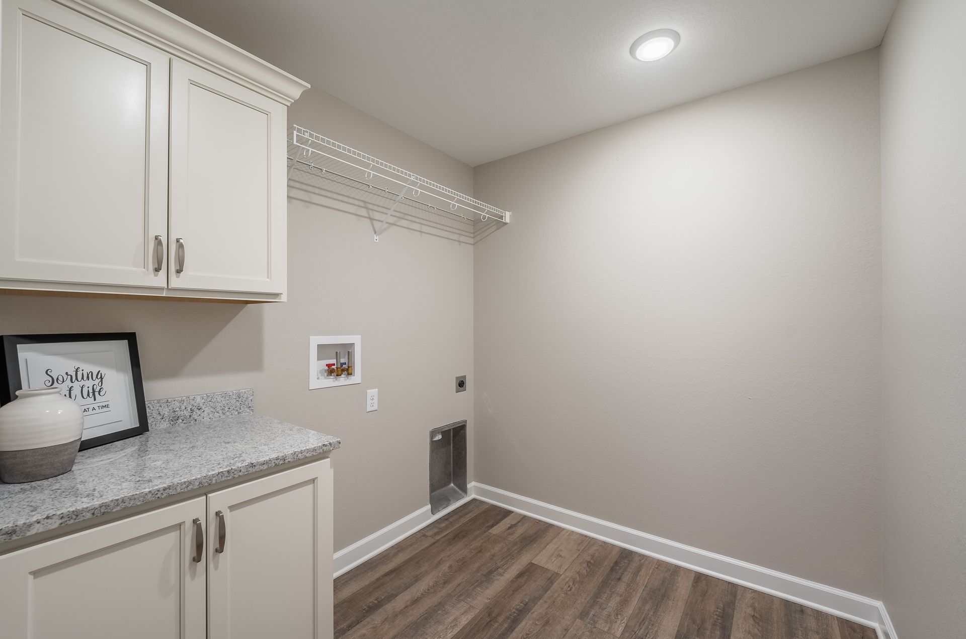 A laundry room in a house with white cabinets and wooden floors.