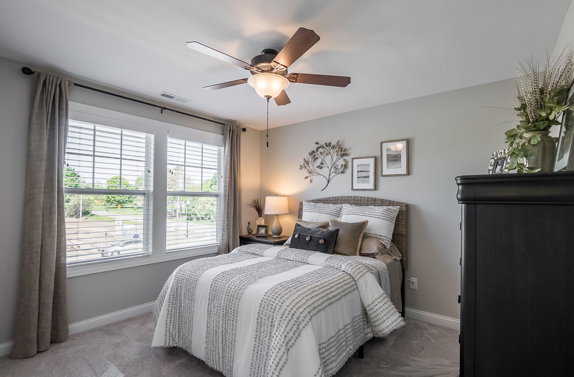 A bedroom with a bed , dresser , and ceiling fan.