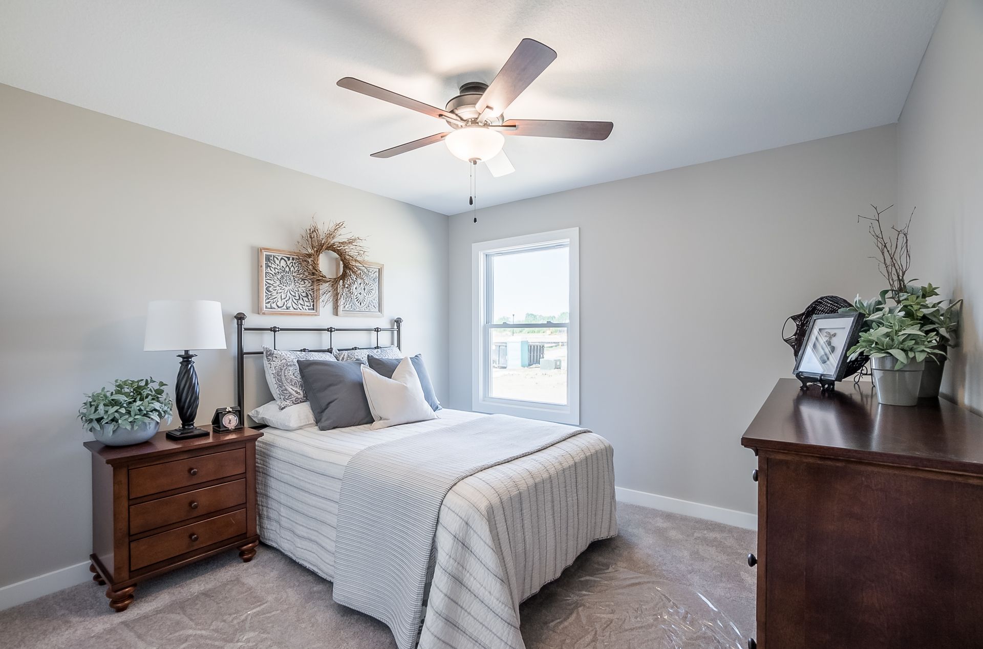 A bedroom with a bed , nightstand , dresser and ceiling fan.