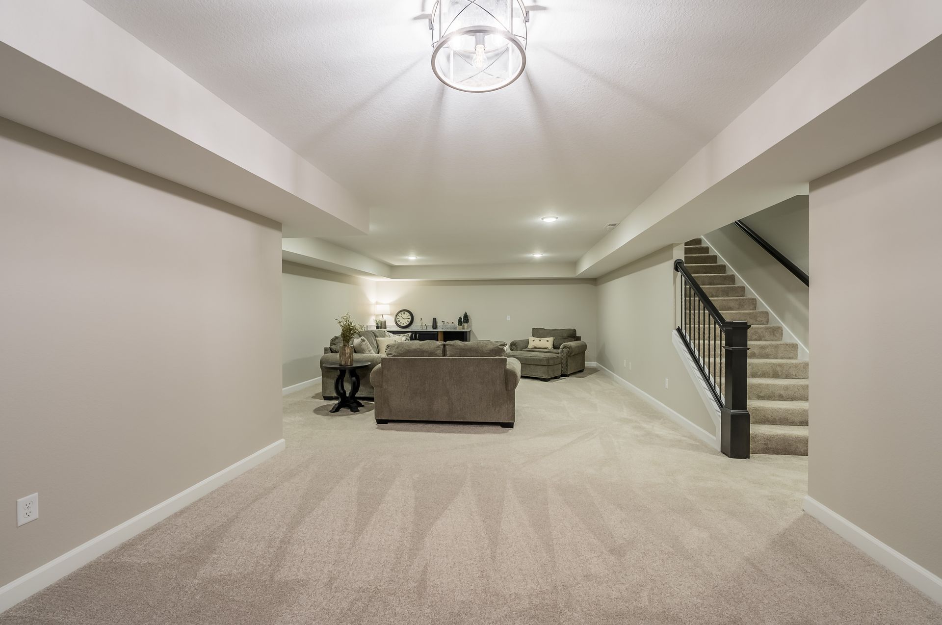 A basement with a living room , stairs and a chandelier.
