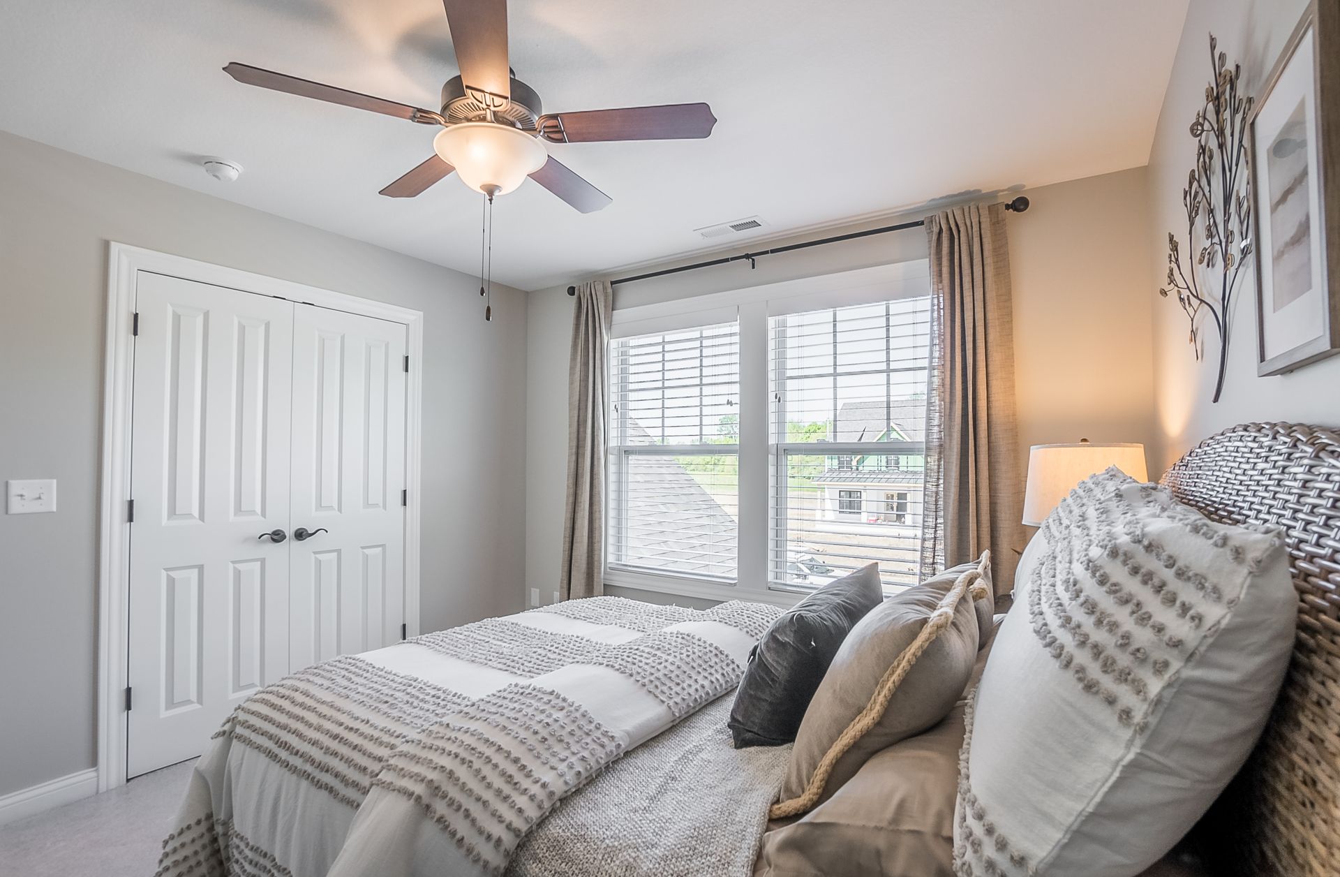 A bedroom with a bed , ceiling fan , and two windows.