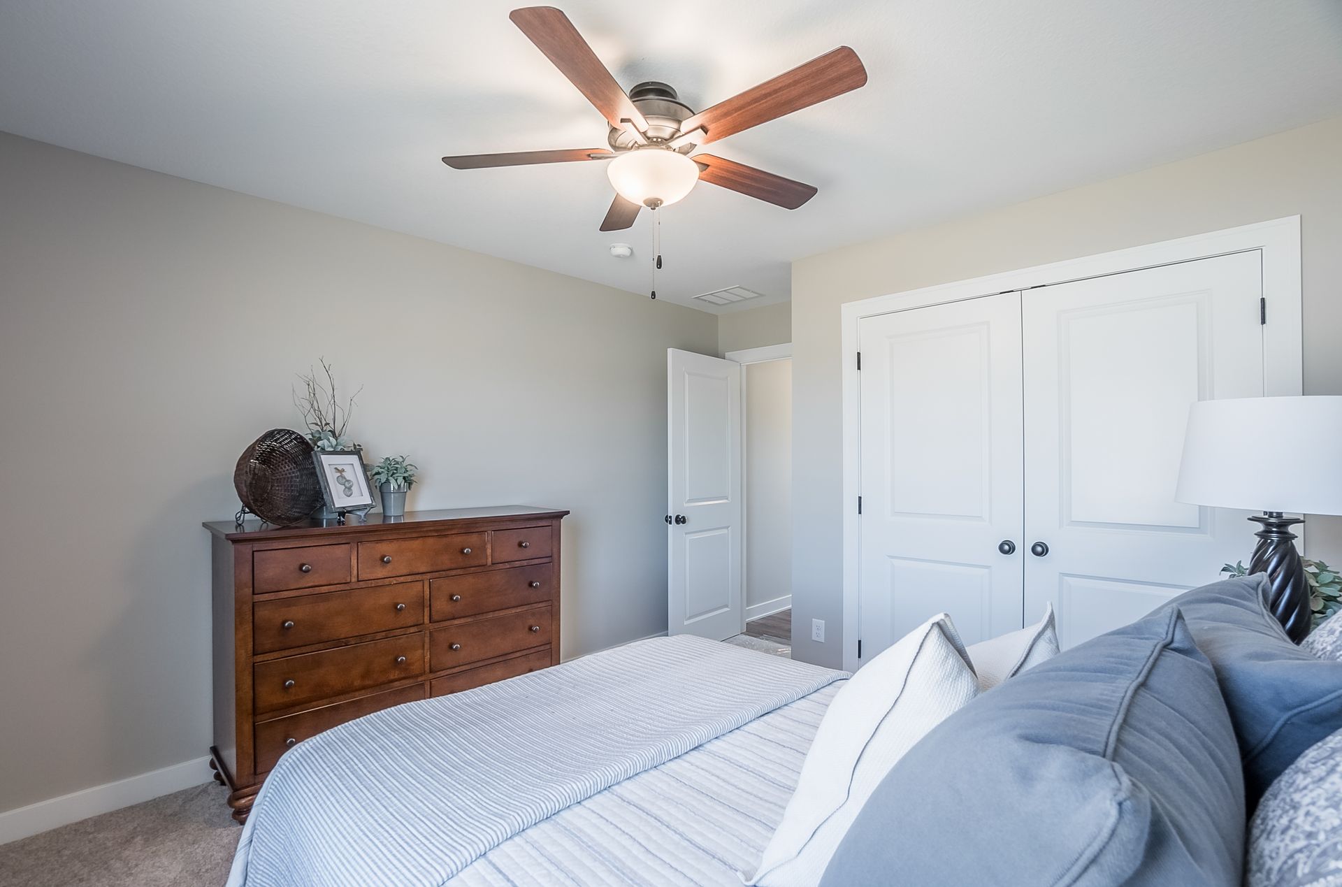 A bedroom with a bed , dresser , and ceiling fan.