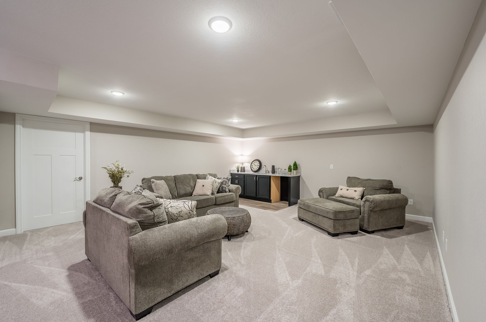 A living room in a basement with a couch and chairs.