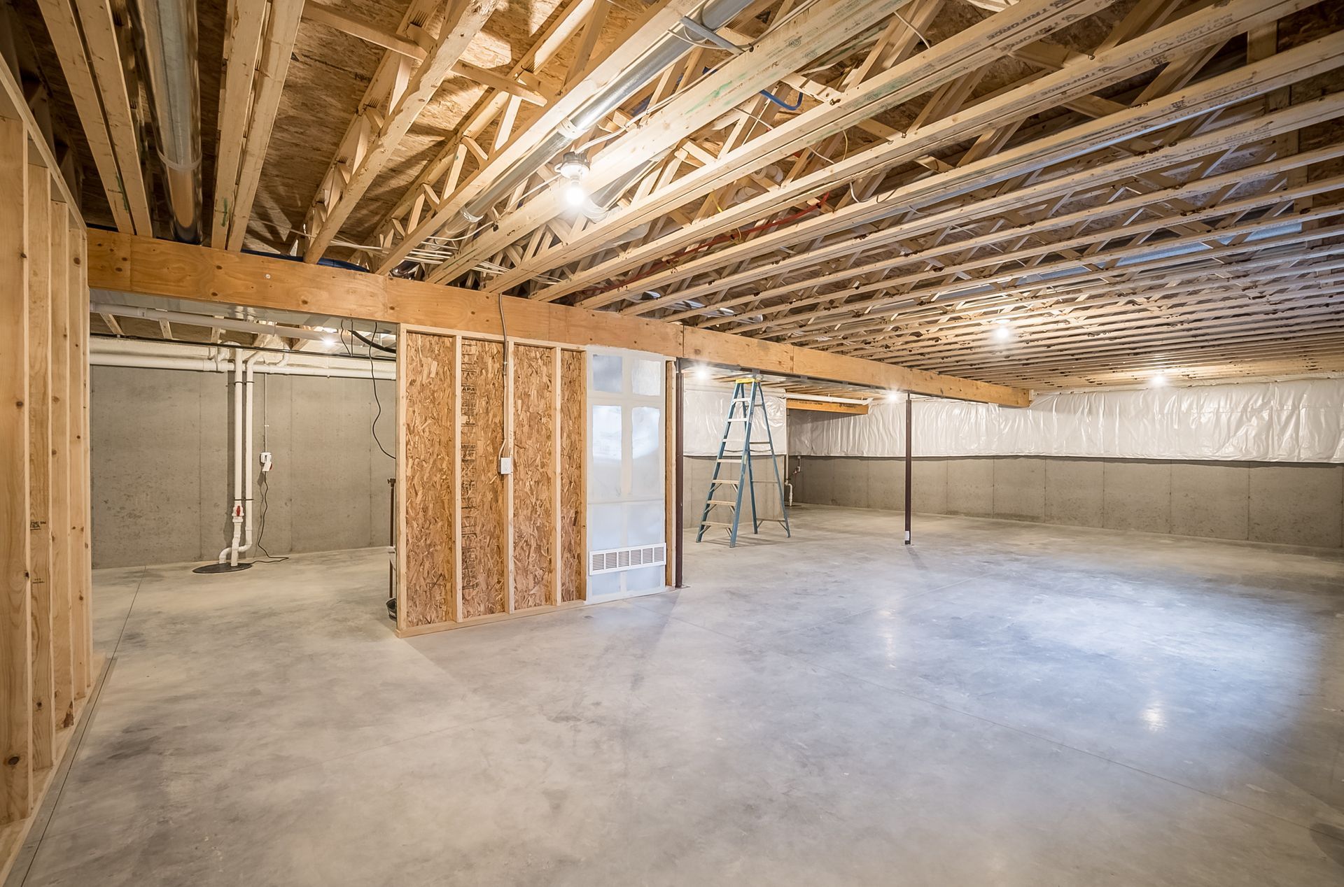 An empty basement with a wooden ceiling and concrete floor.
