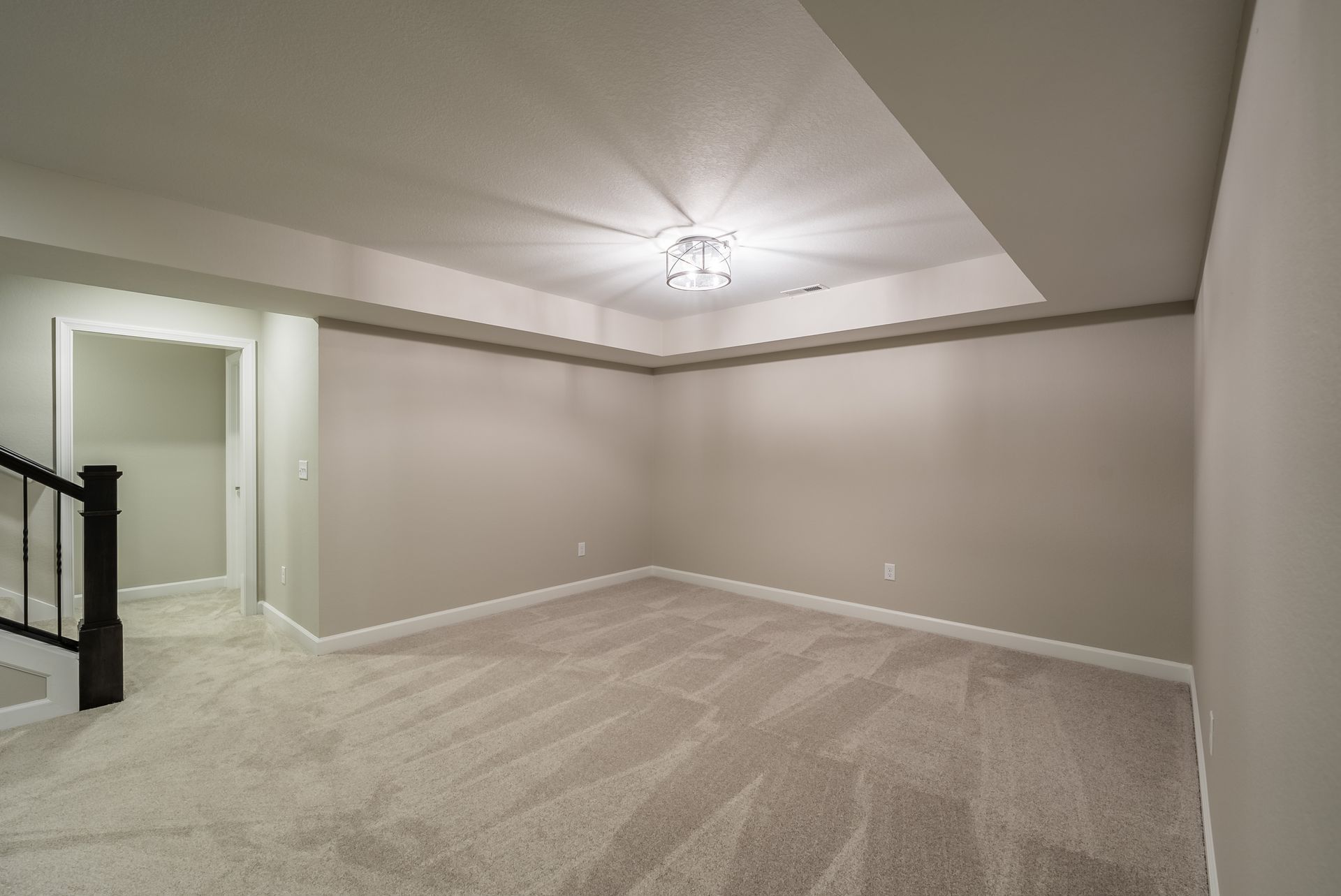 An empty basement with a ceiling fan and a staircase.