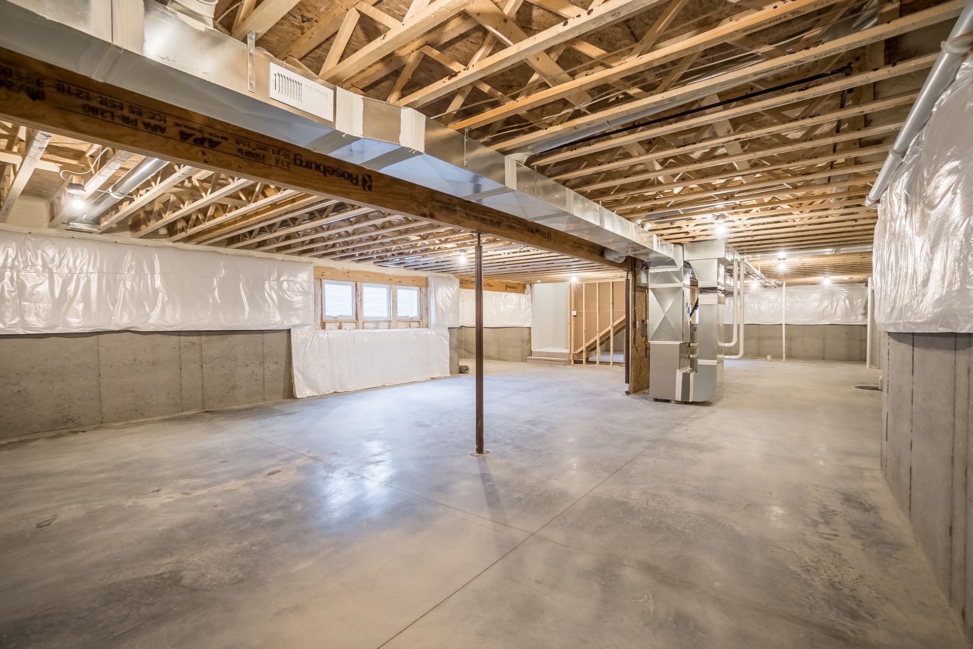 An empty basement with a wooden ceiling and concrete floor.