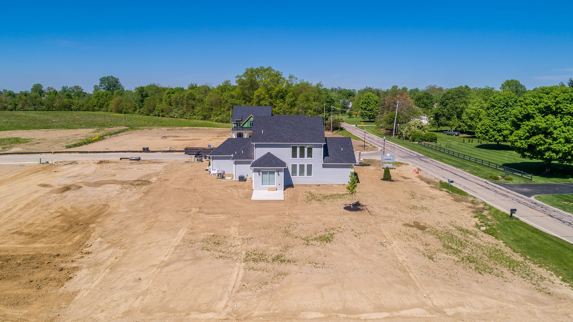 An aerial view of a house sitting on top of a dirt field next to a road.