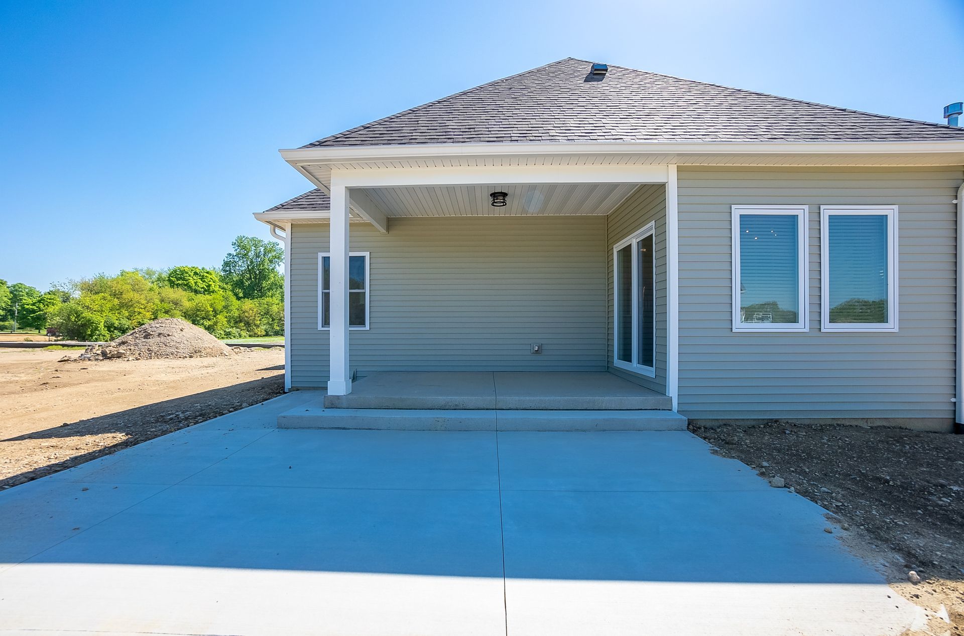 A house with a covered porch and a concrete driveway in front of it.