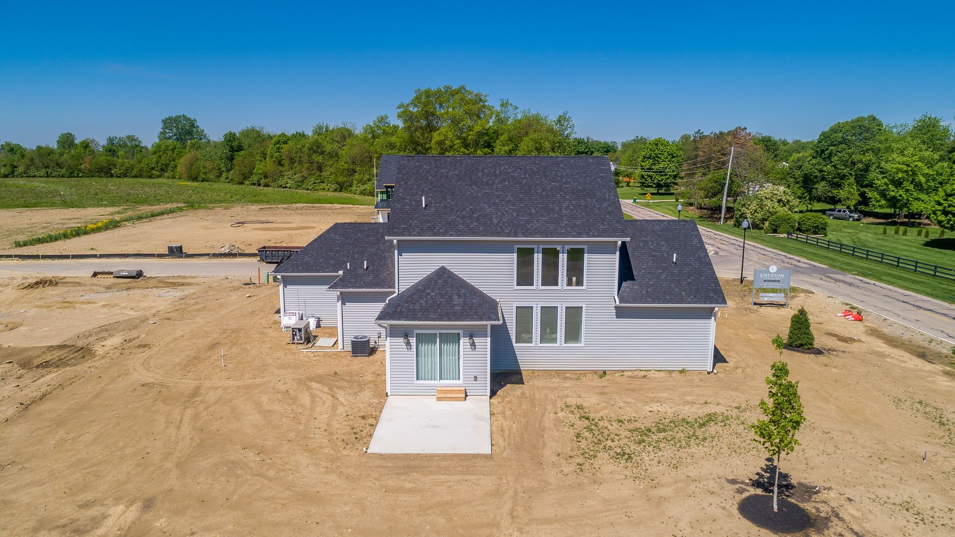 An aerial view of a white house with a black roof in a dirt field.