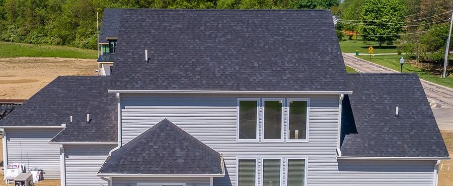 An aerial view of a large white house with a black roof.