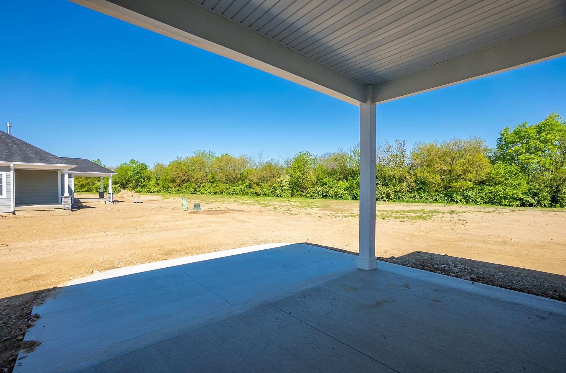 An empty covered patio with a house in the background