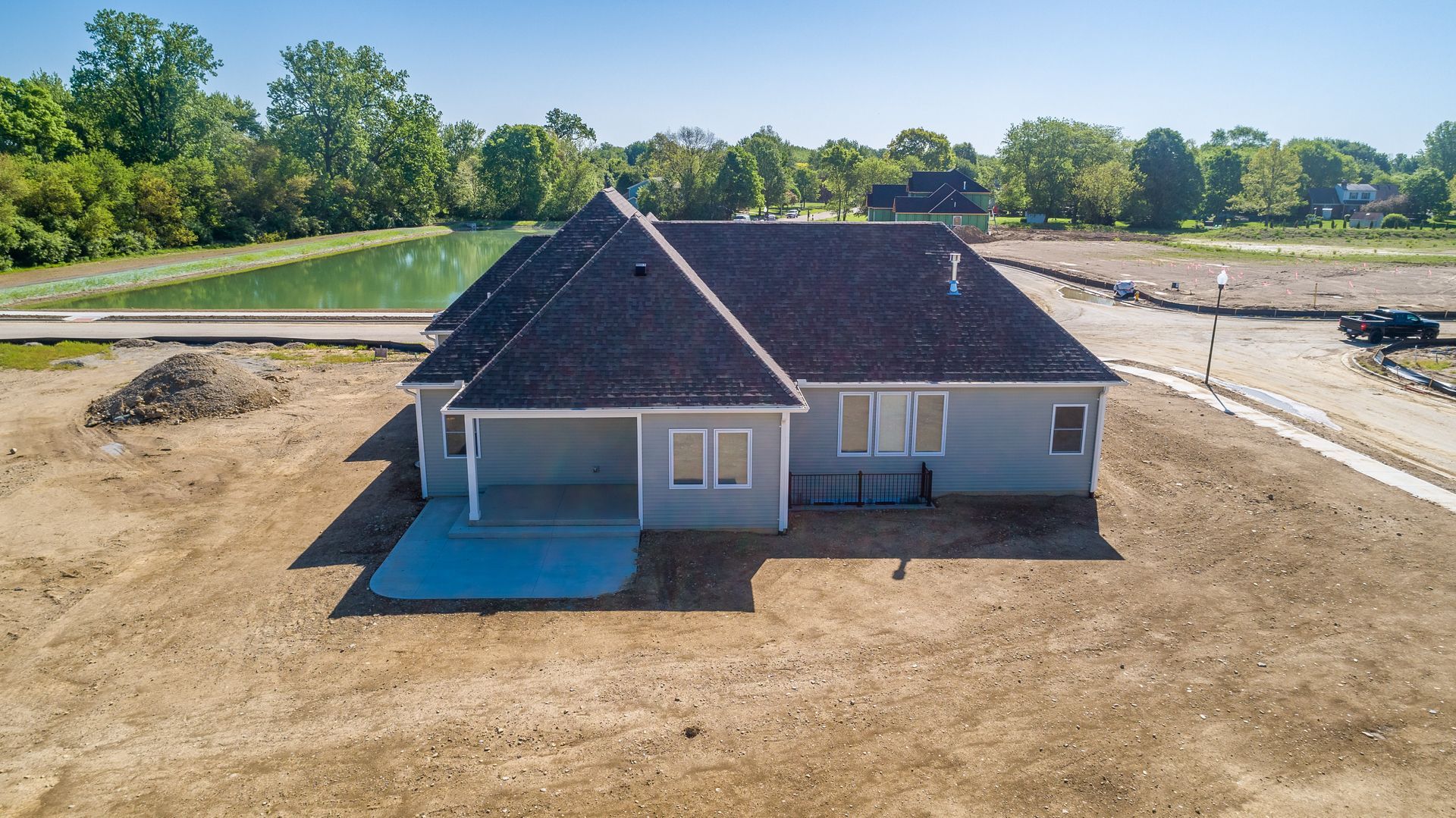 An aerial view of a house under construction with a pond in the background.
