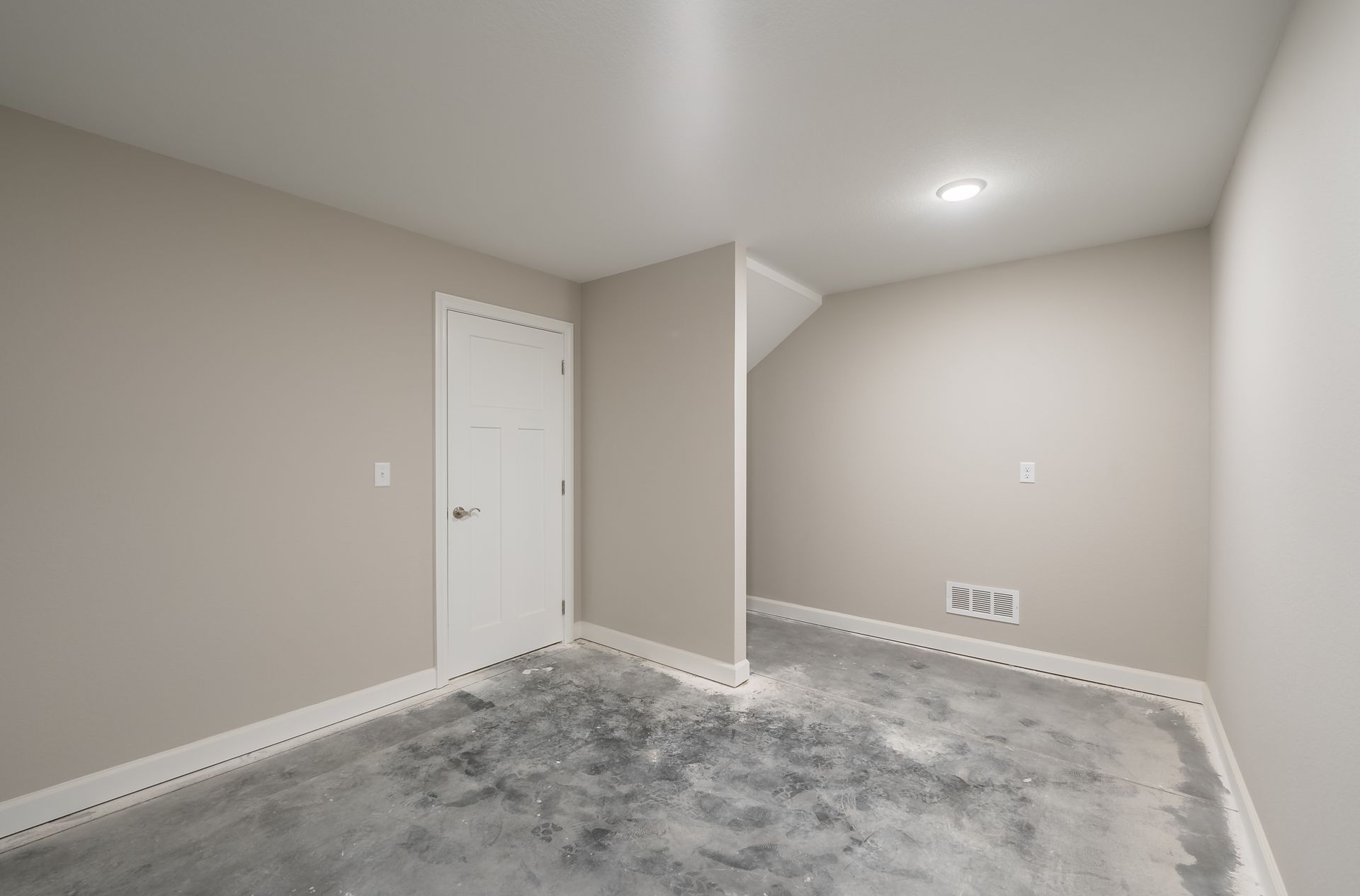 An empty room with a concrete floor and a door.