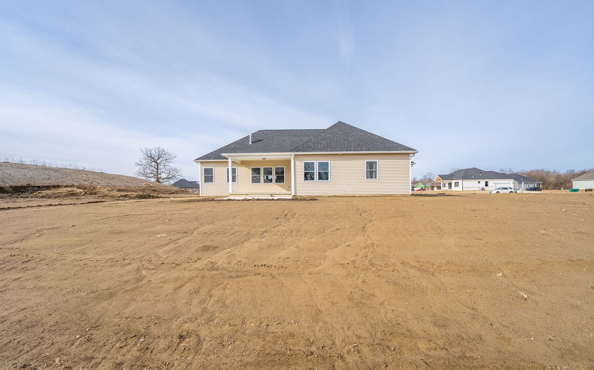 A house is sitting in the middle of a dirt field.
