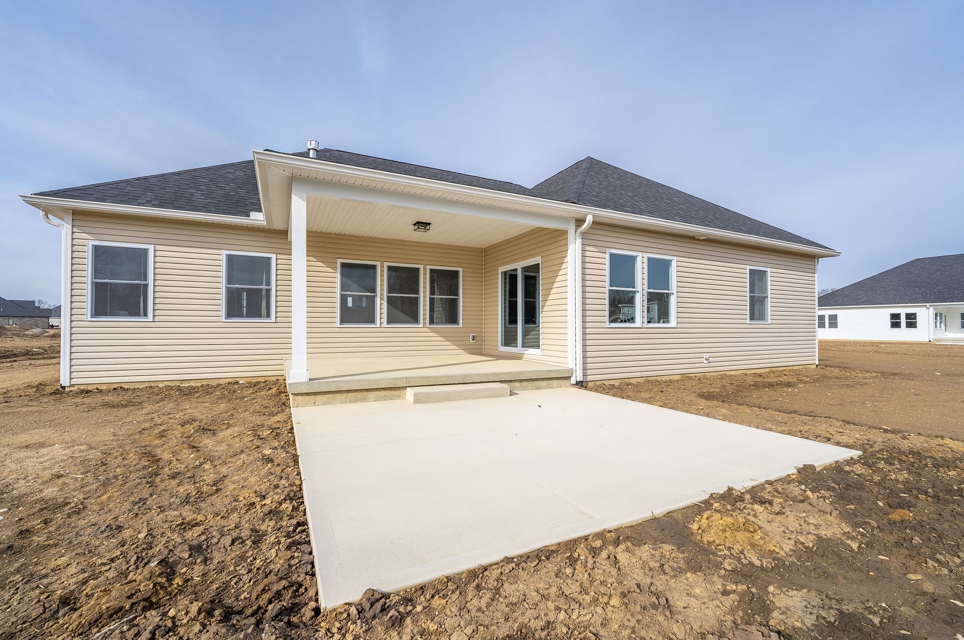 The back of a house with a concrete driveway in front of it.