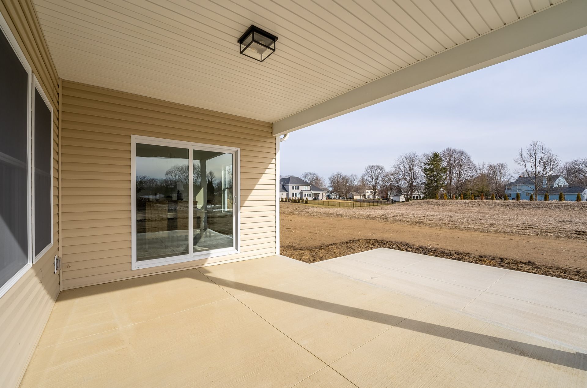 A patio with a sliding glass door and a view of a field.