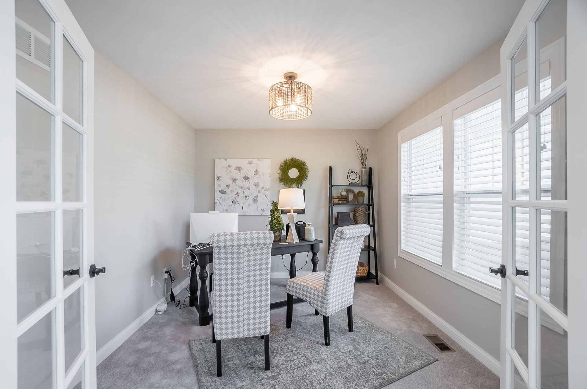 A home office with a desk and chairs and french doors.