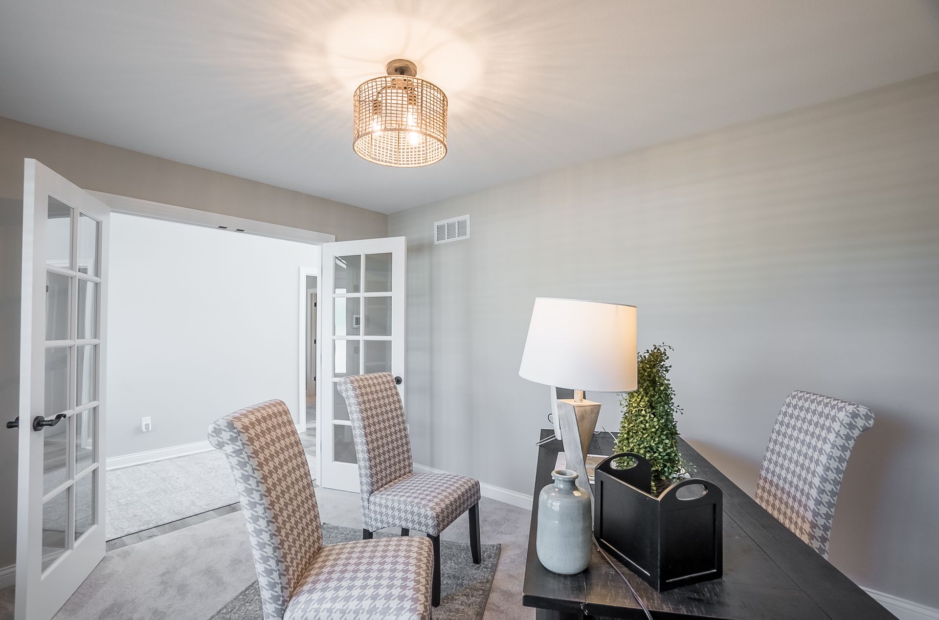 A dining room with a table and chairs and a lamp.