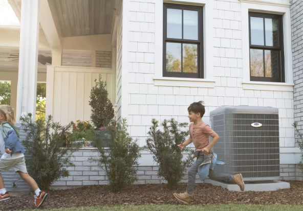 A boy and a girl are running in front of a white house.