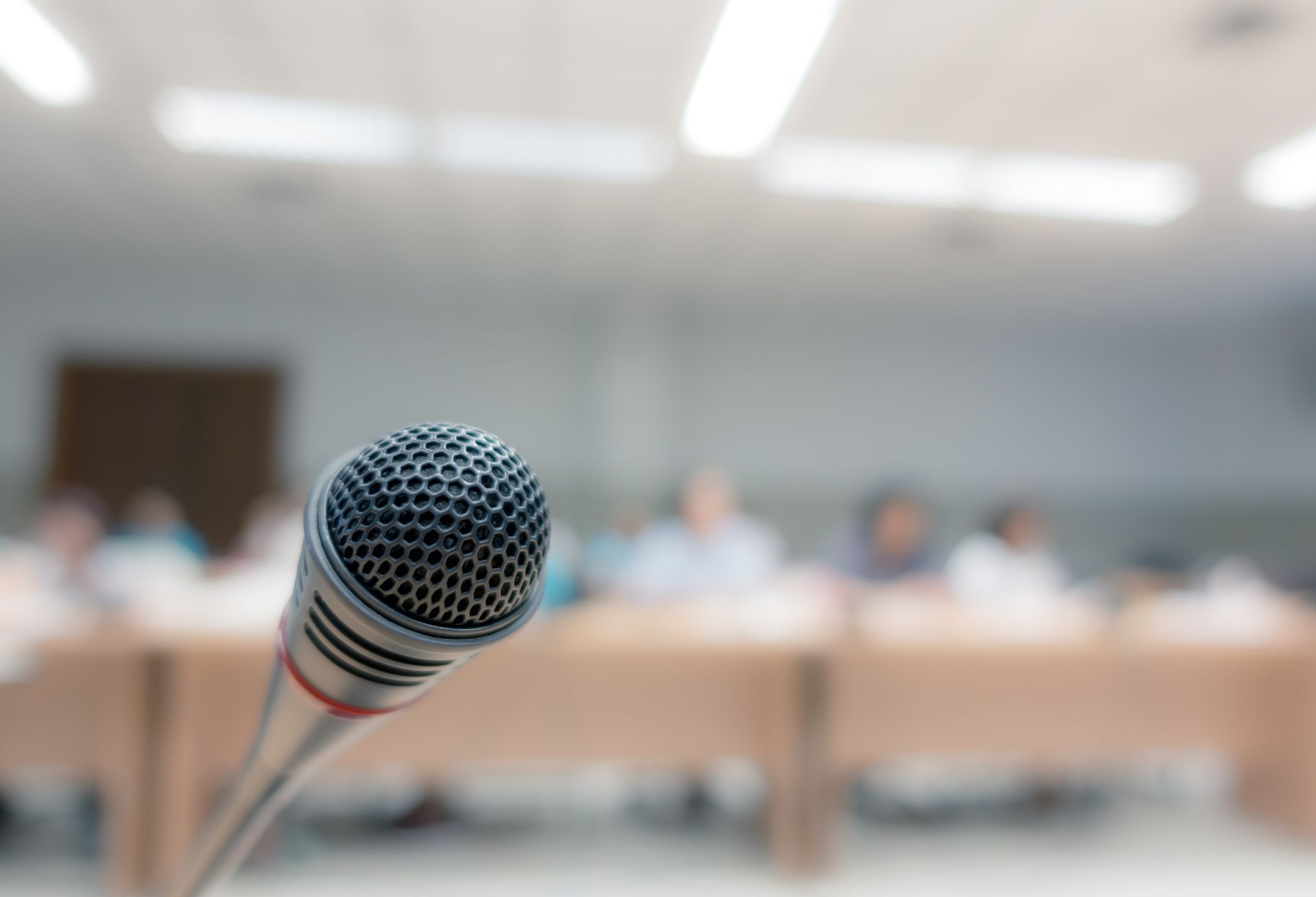 A person wearing glasses and a headset speaks into a microphone while sitting in a soundproof translation booth.