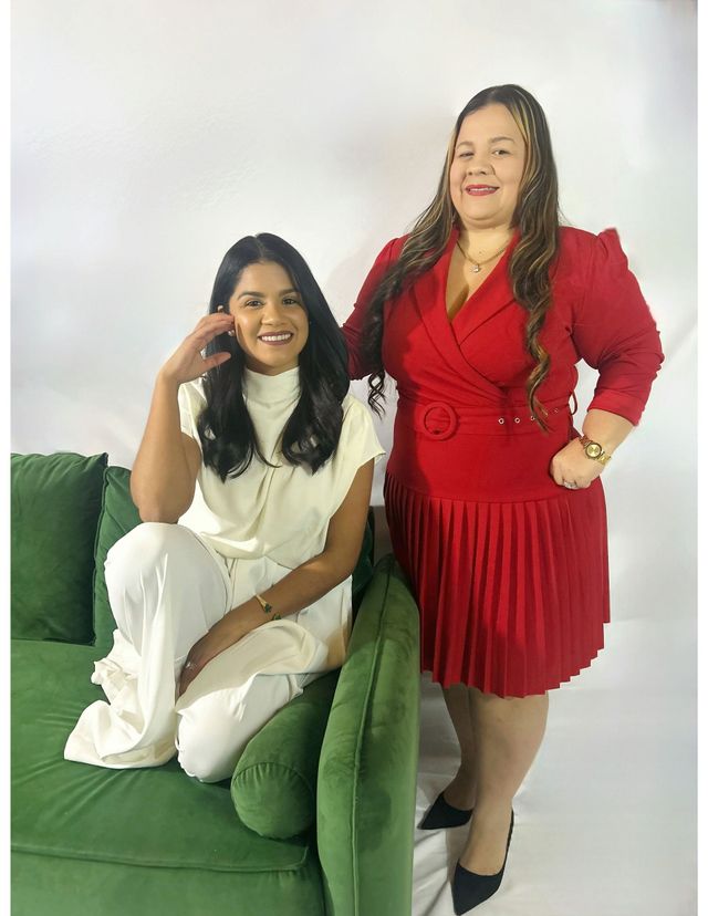 Two women are posing for a picture and one is wearing a red dress